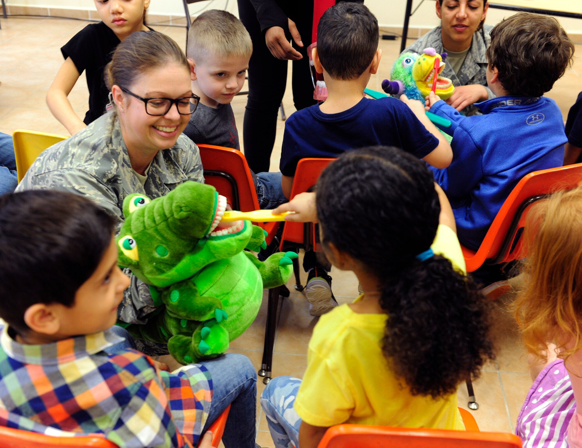 U.S. Air Force Master Sgt. Emily Jones, 39th Medical Operations Squadron dental flight chief, holds a puppet as children from the Incirlik Unit School demonstrate proper toothbrush technique Feb. 19, 2016, at Incirlik Air Base, Turkey. Proper technique ensure the toothbrush reaches the gums and tooth at an angle to best remove the most debris. (U.S. Air Force photo by Staff Sgt. Jack Sanders)