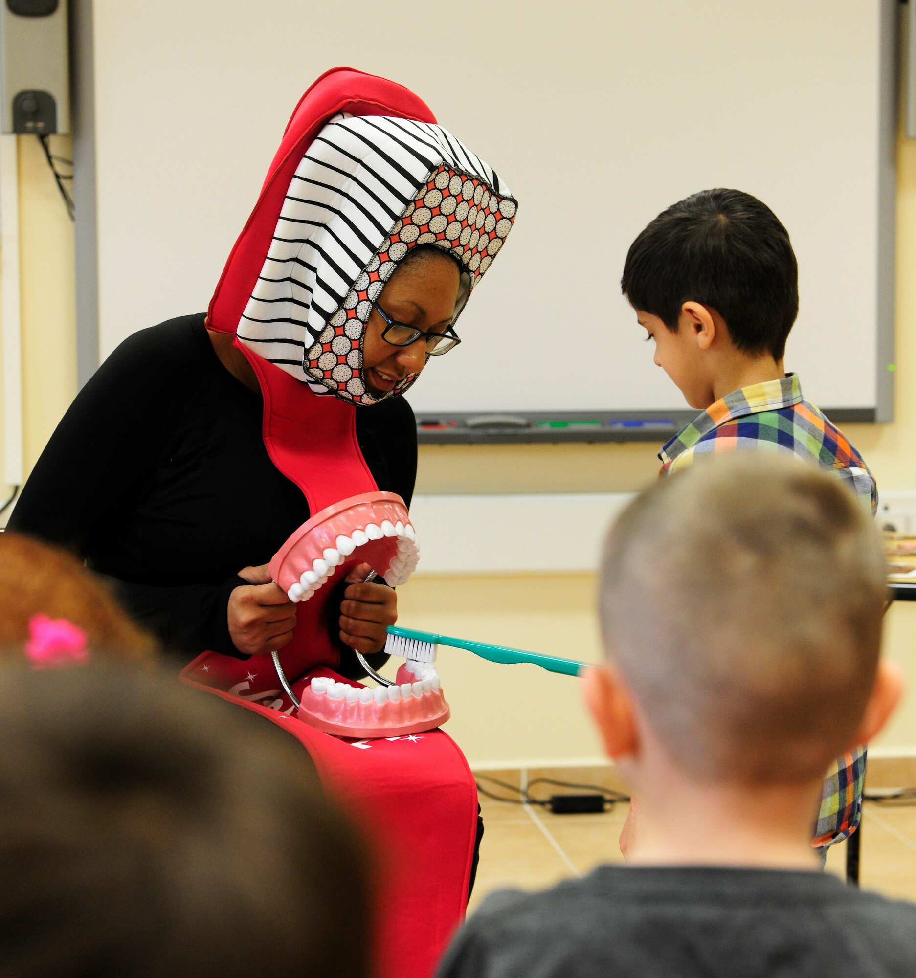 U.S. Air Force Staff Sgt. Harlandria Moses, 39th Medical Operations Squadron oral preventative technician, instructs a child from Incirlik Unit School on the proper technique for brushing teeth at Incirlik Air Base, Turkey Feb. 19, 2016. Members of the dental flight informed the children how foods and tooth care affect oral health. (U.S. Air Force photo by Staff Sgt. Jack Sanders)