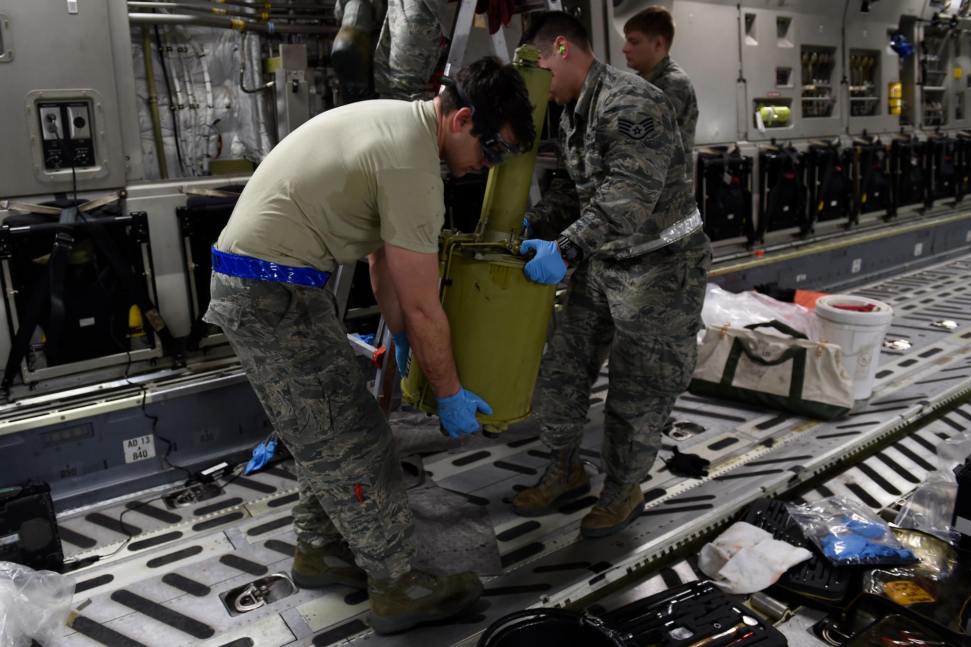 Senior Airman Jacob Remstrom (right) 62nd Maintenance Squadron hydraulics systems specialist and Staff Sgt. Jeremy Aiumo, 62nd Aircraft Maintenance Squadron crew chief, remove a hydraulic reservoir Feb. 18, 2016 at North Island Naval Station, Calif. Aiumo was on the McChord Maintenance Recovery Team to remove the flare system off the C-17 Globemaster III, but helped out anyway he could to get the mission done faster. (U.S. Air Force photo/Tech Sgt. Tim Chacon)