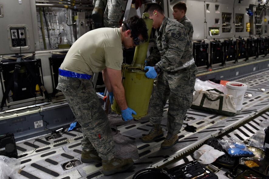 Senior Airman Jacob Renstrom (right) 62nd Maintenance Squadron hydraulics systems specialist and Staff Sgt. Jeremy Aiumo, 62nd Aircraft Maintenance Squadron crew chief, remove a hydraulic reservoir Feb. 18, 2016 at North Island Naval Station, Calif. Aiumo was on the McChord Maintenance Recovery Team to remove the flare system off the C-17 Globemaster III, but helped out anyway he could to get the mission done faster. (U.S. Air Force photo/Tech Sgt. Tim Chacon) 
