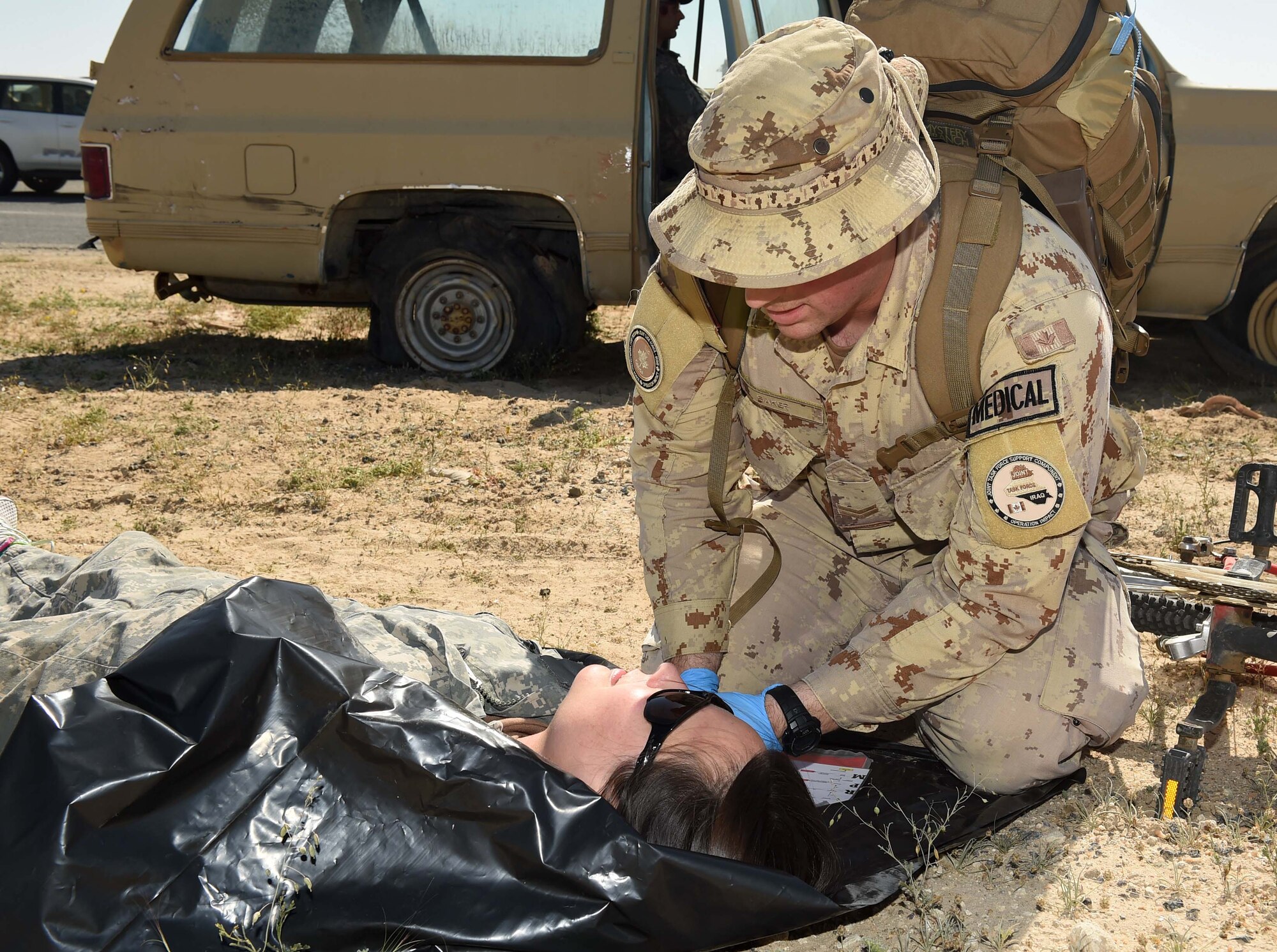 A Canadian Armed Forces medic assesses a mock casualty during a joint medical exercise Feb. 18, 2016, at an undisclosed location in Southwest Asia. The 386th Air Expeditionary Wing partnered with soldiers from the 41st Combat Aviation Brigade and coalition forces medical personnel to conduct a medical exercise to test readiness and response times for first responders. (U.S. Air Force photo by Staff Sgt. Jerilyn Quintanilla)