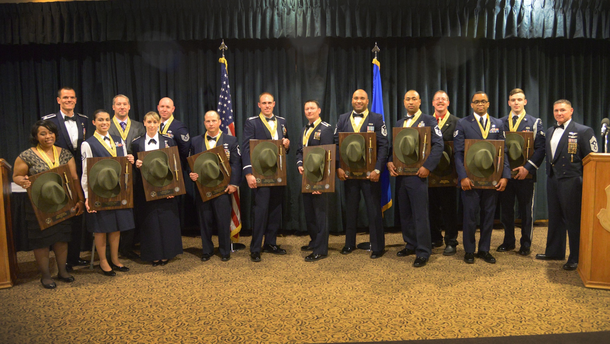All 13 top award winners stand with Col. Ben Maitre, 27th SOW commander, and Chief Master Sgt. Randy Scanlan, 27th SOW command chief, after individually receiving their annual award trophy Feb. 19, 2016, at Cannon Air Force Base, N.M. The 13 members of Team Cannon represent the best of 2015 in the categories of: airman; noncommissioned officer;  senior NCO; company grade officer; field grade officer; additional duty first sergeant; first sergeant; civilian categories I, II and III; key spouse; honor guardsman; and volunteer of the year. (U.S. Air Force photo/Staff Sgt. Alexx Pons) 
