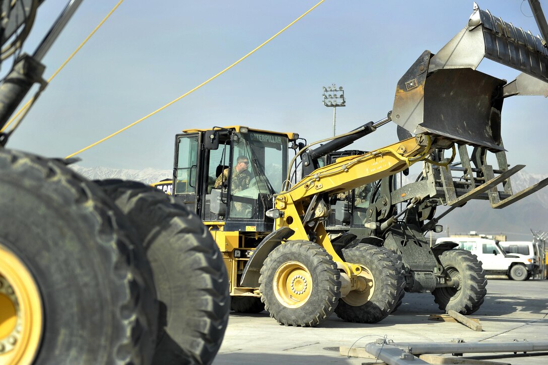 Air Force Staff Sgt. Ranson Holt operates a front-end loader to stabilize a rib from a large maintenance shelter on the flight line on Bagram Airfield, Afghanistan, Feb. 12, 2016. Holt is a heavy-equipment operator assigned to the 455th Expeditionary Civil Engineer Squadron. The structure was moved on the base and will soon be the new C-130 Hercules aircraft parts store, creating a larger and more convenient facility than the current one. Air Force photo by Capt. Bryan Bouchard