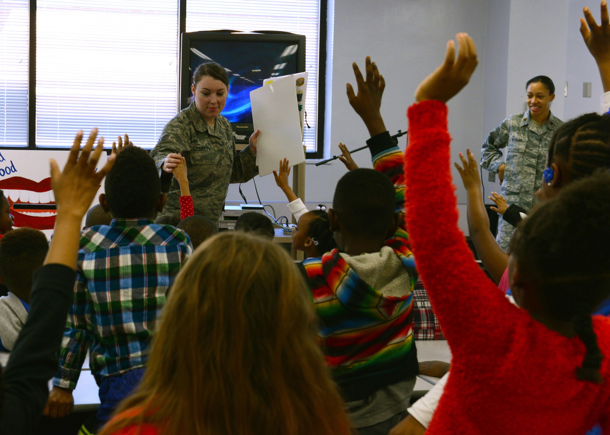 U.S. Air Force Staff Sgt. Tonya L. Collett, 20th Dental Squadron non-commissioned officer in charge of preventative dentistry, plays a learning game with children at Willow Drive Elementary School in Sumter, S.C., Feb. 18, 2016. The game challenged children to identify healthy and unhealthy foods for their teeth. (U.S. Air Force photo by Airman 1st Class Destinee Dougherty)