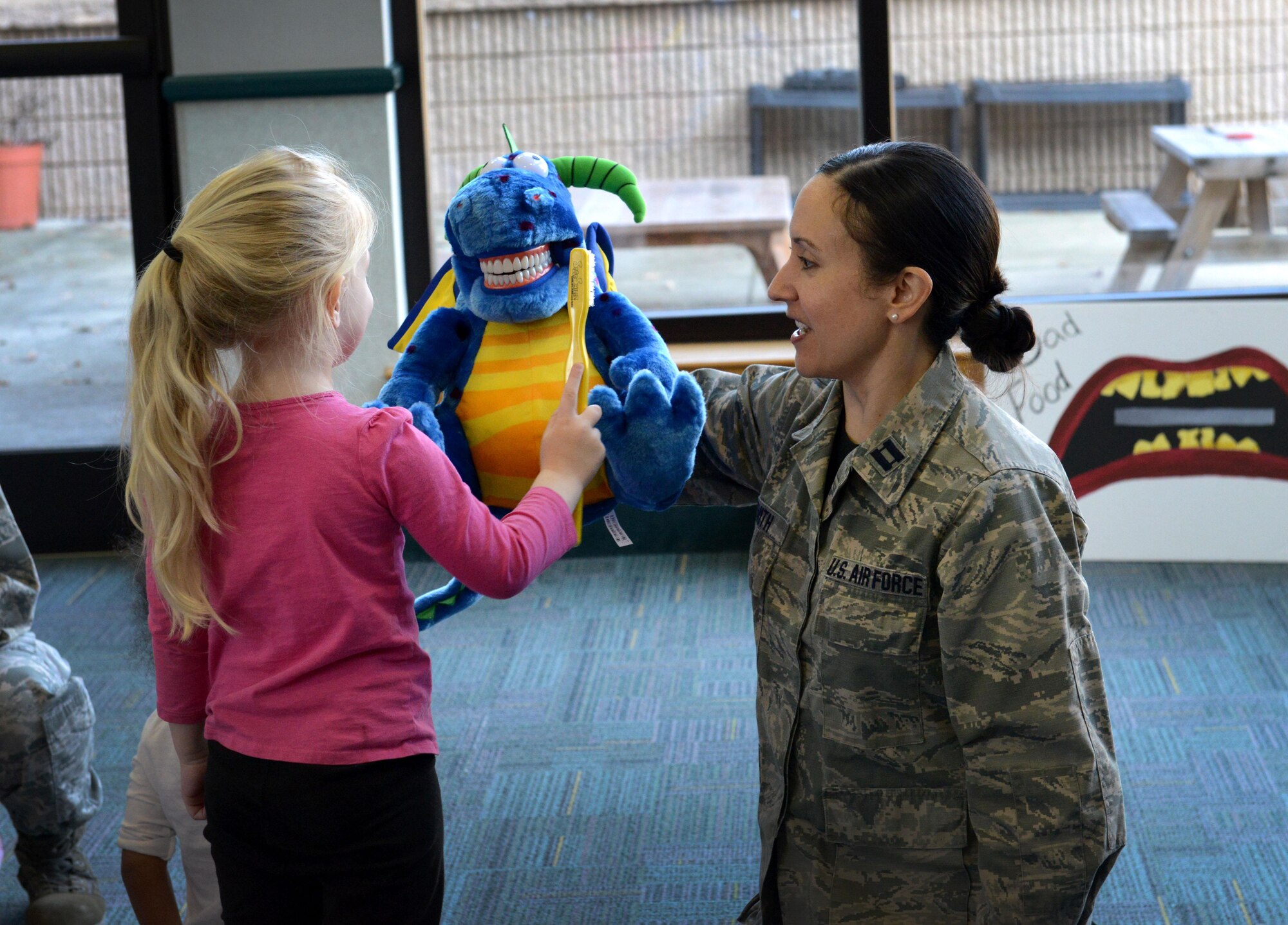 U.S. Air Force Capt. (Dr.) Jamie Smith, 20th Dental Squadron general dentist, lets children brush the teeth of a dragon puppet at the Child Development Center at Shaw Air Force Base, S.C., Feb. 19, 2016. The 20th DS visited various schools in Sumter, S.C., and the CDC on Shaw to teach children about taking care of their teeth. (U.S. Air Force photo by Airman 1st Class Destinee Dougherty)