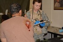 Fort Knox, Ky. A student from the 100th Division's 68W10 (Army Medic) MOS-T course, Phase 3 (early 2015), assesses her patient during the Battalion Aid Station (BAS) portion of training. This phase of training simulates practical situations that Soldiers may face in a deployed environment. Soldiers are graded and mentored as they advance through the phases of this course and are returned to their units with the working knowledge and skills to serve as Army Medics for the US Army Reserve, with the ability to mobilize and serve the active duty army overseas.(Army photo by: 1LT Alicia Carver, 100th TD)