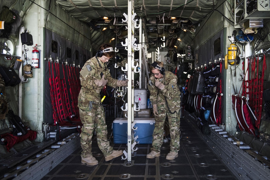 Air Force Capt. Tracie Coy, left, and Senior Airman Haley Lecomte adjust the configuration inside a C-130 Hercules aircraft during an aerial medical evacuation mission on Al Udeid Air Base, Qatar, Feb. 11, 2016. Coy and Lecomte are assigned to the 379th Expeditionary Aeromedical Evacuation Squadron. Air Force photo by Staff Sgt. Corey Hook