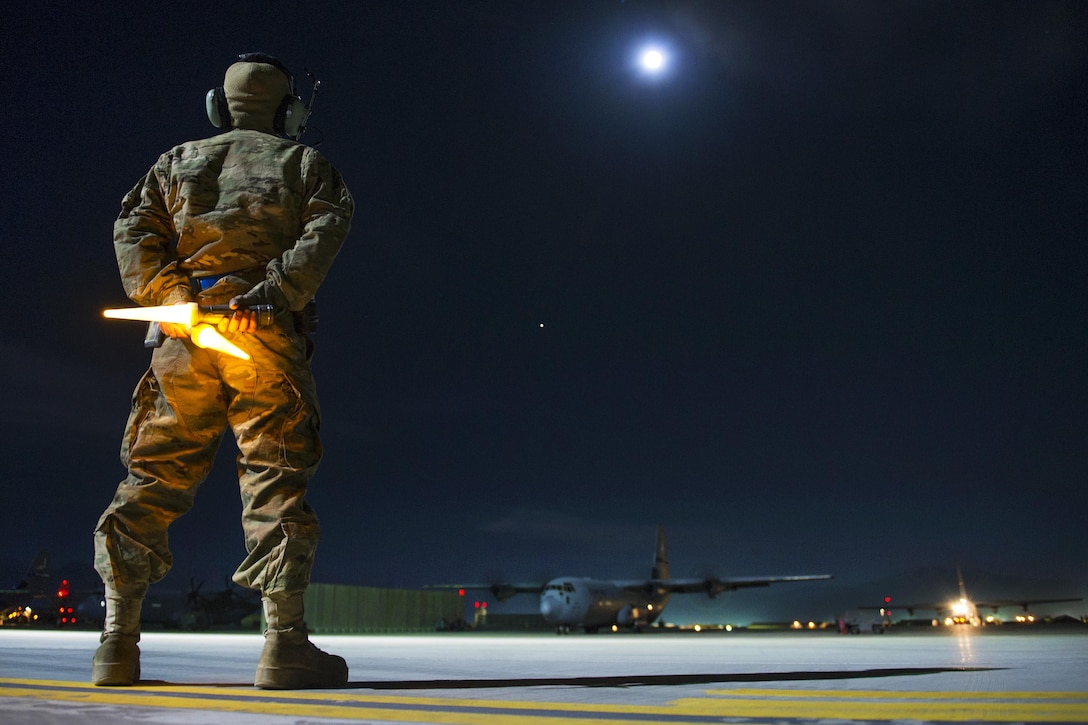 Air Force Senior Airman Alec Flores prepares to guide a C-130J Super Hercules aircraft onto a taxiway as it leaves on a night sortie on Bagram Airfield, Afghanistan, Feb. 22, 2016. Flores is a crew chief assigned to the 455th Expeditionary Aircraft Maintenance Squadron. Air Force photo by Tech. Sgt. Robert Cloys