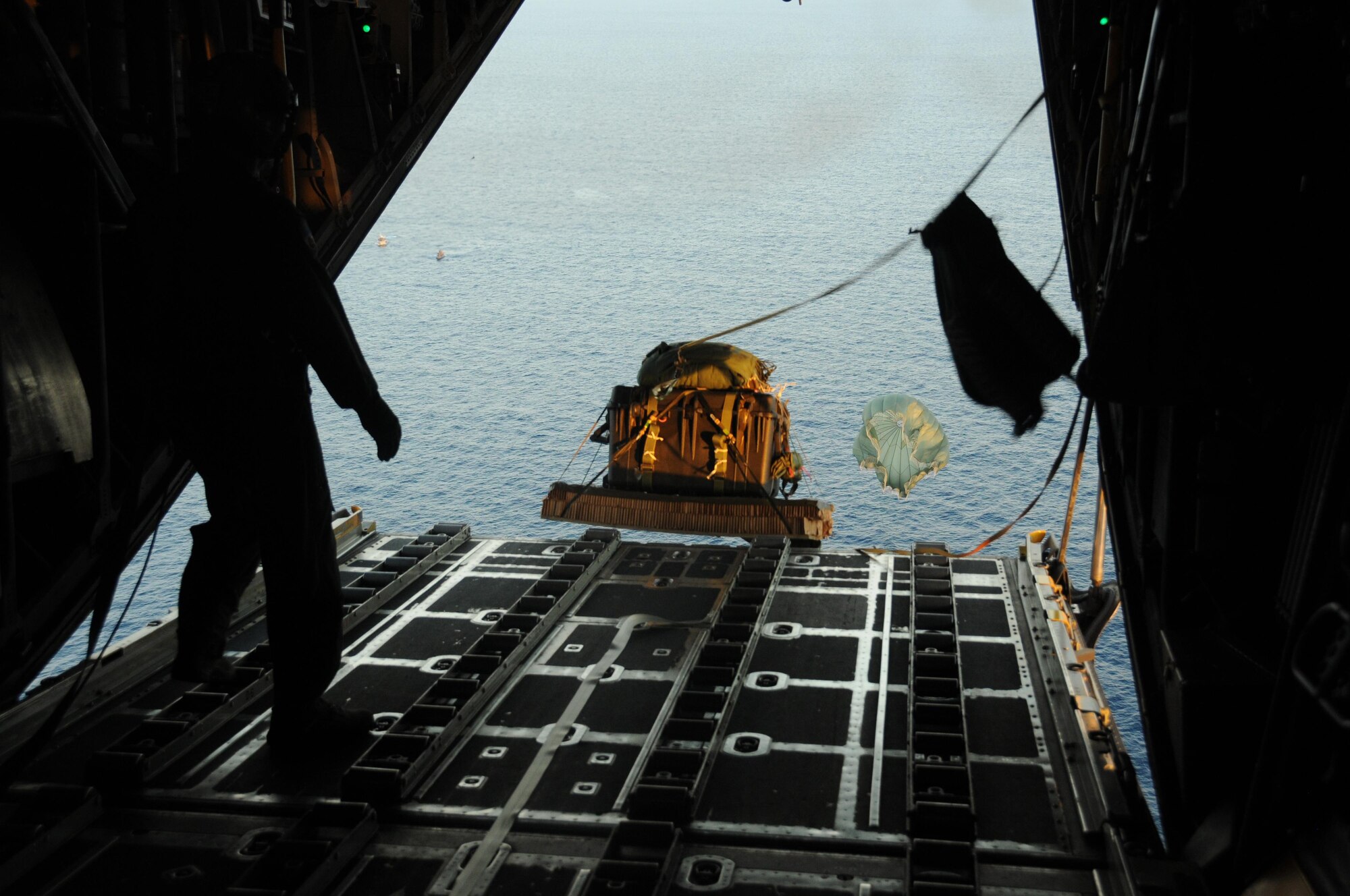 Pallets are pushed over the end of a ramp in the back of a C-130 hercules over the Pacific Ocean on Jan. 29, 2016. The pallets were full of supplies that were a part of a concept operation. (U.S. Air Force Photo by Senior Airman Miles Wilson)