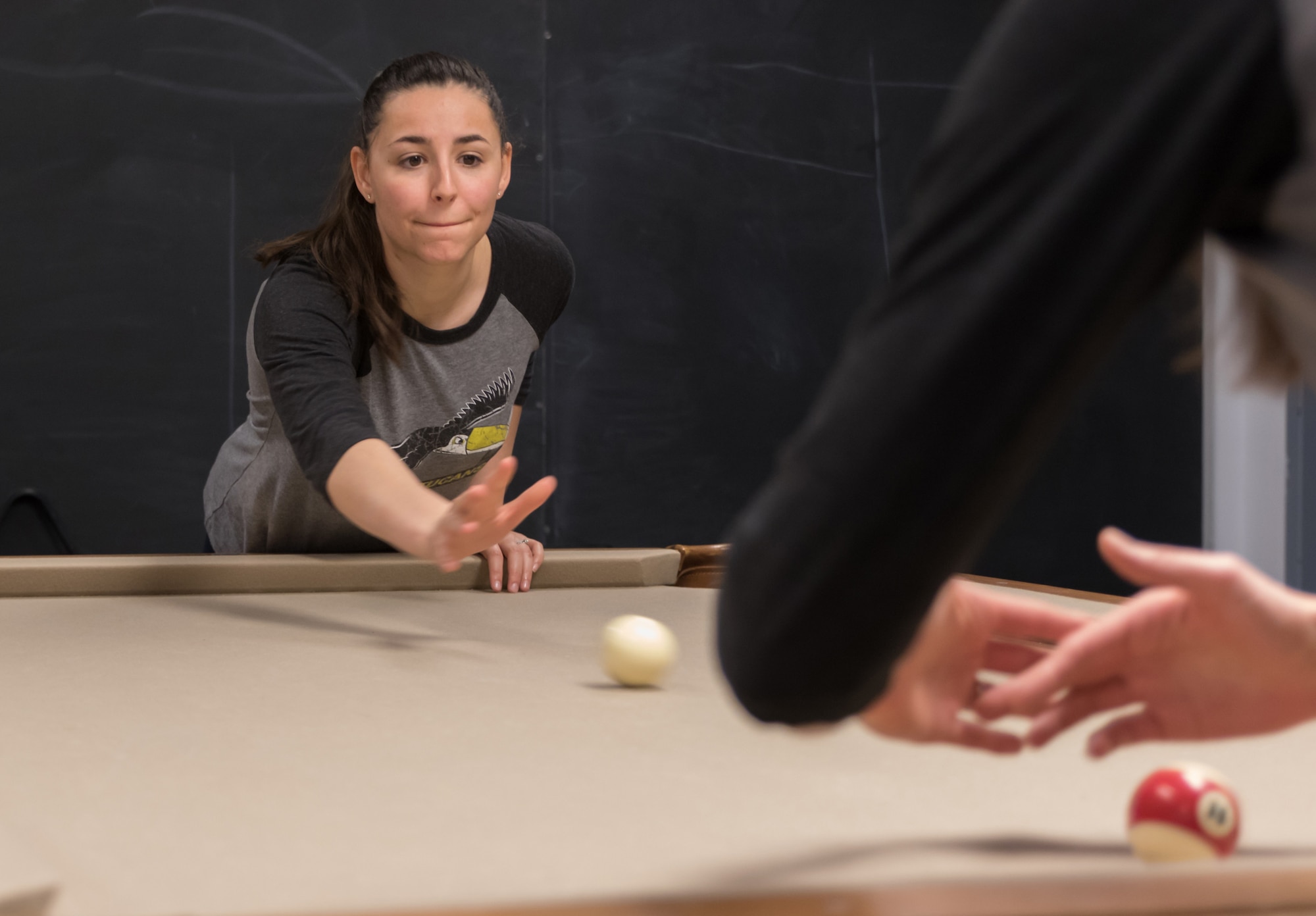 Caitlin Dettwiler, a spouse in the 71st Student Squadron, throws the ball in an opening serve during Crud practice Feb. 23, in the 71st STUS heritage room. Dettwiler is training for the Ladies Crud tournament scheduled for 6 p.m., March 4, at the Vance Collocated Club. (Photo by Lt. Col. Mike Drost)