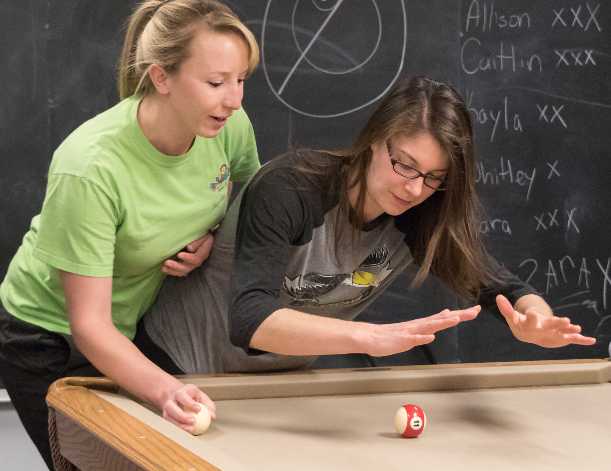 Whitley Johnson, left, a spouse in the 3rd Flying Training Squadron, takes a shot as 71st Student Squadron spouse, Amber Mocalis, blocks during Crud practice Feb. 23, in the 71st STUS heritage room. Johnson and Mocalis are training for the Ladies Crud tournament scheduled for 6 p.m., March 4, at the Vance Collocated Club. (Photo by Lt. Col. Mike Drost)