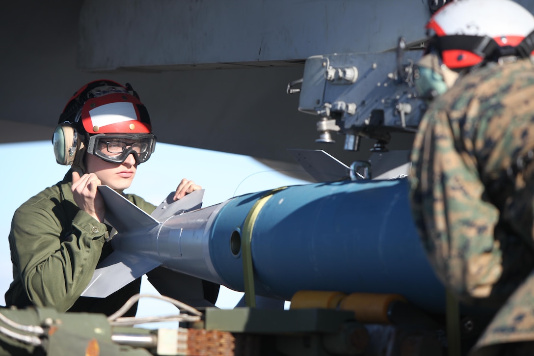 Lance Cpl. Stephen Tryen assists in lifting a BDU-45 practice bomb onto an F/A-18 Hornet during Exercise Coastal Predator at Marine Corps Air Station Cherry Point, N.C., Feb. 16, 2016. The practice bomb falls according to the trajectory of the aircraft while in flight and is used for training purposes. Coastal Predator is an exercise that included Marine Corps and Army aviation assets along with Air Force personnel and civilian contractors to conduct Forward Air Controller Airborne training in accordance with the pre-deployment training program. Tryen is an ordnance technician with Marine All Weather Fighter Attack Squadron 533. (U.S. Marine Corps photo by Cpl. Jason Jimenez/Released)