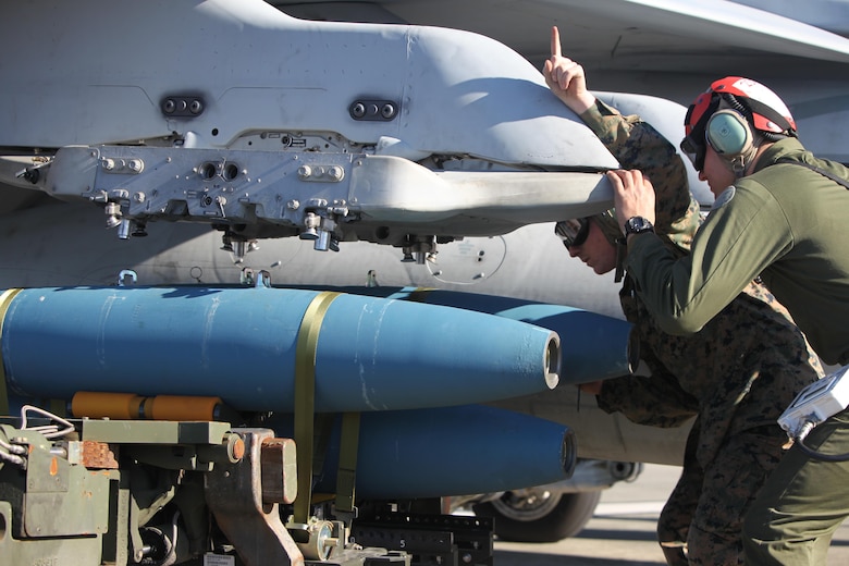 Cpl. Ross McClanahan signals to a Marine operating an A/S 32K-1A/1B/1C SATS Weapon Loader to load BDU-45 practice bombs onto an F/A-18 Hornet during Exercise Coastal Predator at Marine Corps Air Station Cherry Point, N.C., Feb. 16, 2016. The practice bombs are unguided ordnance that falls according to the trajectory of the aircraft while in flight and is used for training purposes. Coastal Predator is an exercise that included Marine Corps and Army aviation assets along with Air Force personnel and civilian contractors to conduct Forward Air Controller Airborne training in accordance with the pre-deployment training program.  (U.S. Marine Corps photo by Cpl. Jason Jimenez/Released)