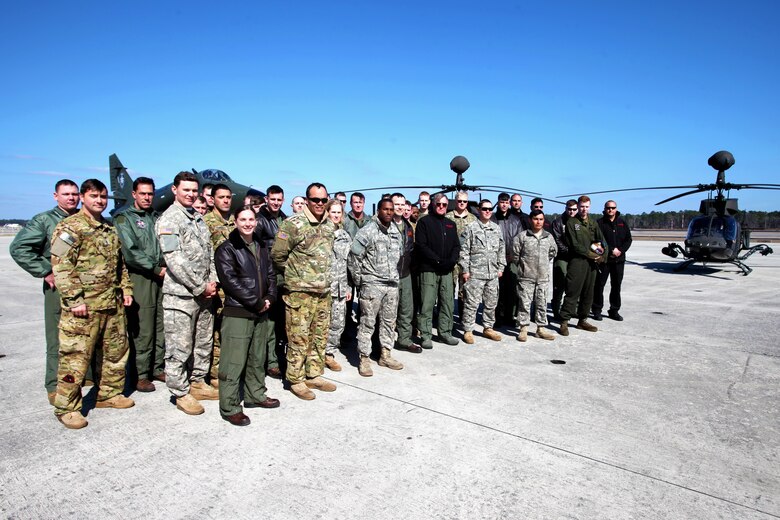 Active duty and retired service members pose for a photo in front of two OH-58 Kiowa’s and an A-4 Skyhawk during Exercise Coastal Predator at Marine Corps Air Station Cherry Point, N.C., Feb. 19, 2016. Coastal Predator is an exercise that included Marine Corps and Army aviation assets along with Air Force personnel and civilian contractors to conduct Forward Air Controller Airborne training in accordance with the pre-deployment training program.  (U.S. Marine Corps photo by Cpl. Jason Jimenez/Released)