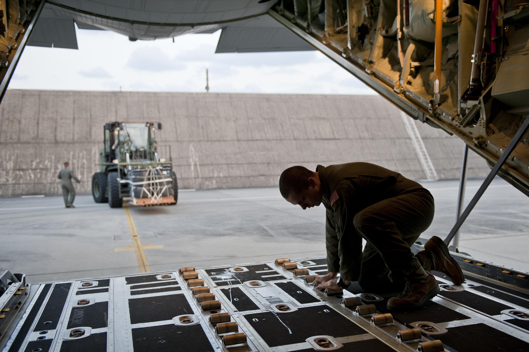 U.S. Air Force Senior Airman Zach Harmon, 17th Special Operations Squadron MC-130J Commando II loadmaster, prepares a cargo deck for loading during a training exercise Feb. 17, 2016, at Kadena Air Base, Japan. Harmon participated in a fast-reaction simulation that tested the squadron's capability to quickly and safely mobilize their entire fleet of aircraft for cargo drops, short runway landings and takeoffs, and helicopter air-to-air refueling. (U.S. Air Force photo by Senior Airman Peter Reft/Released)