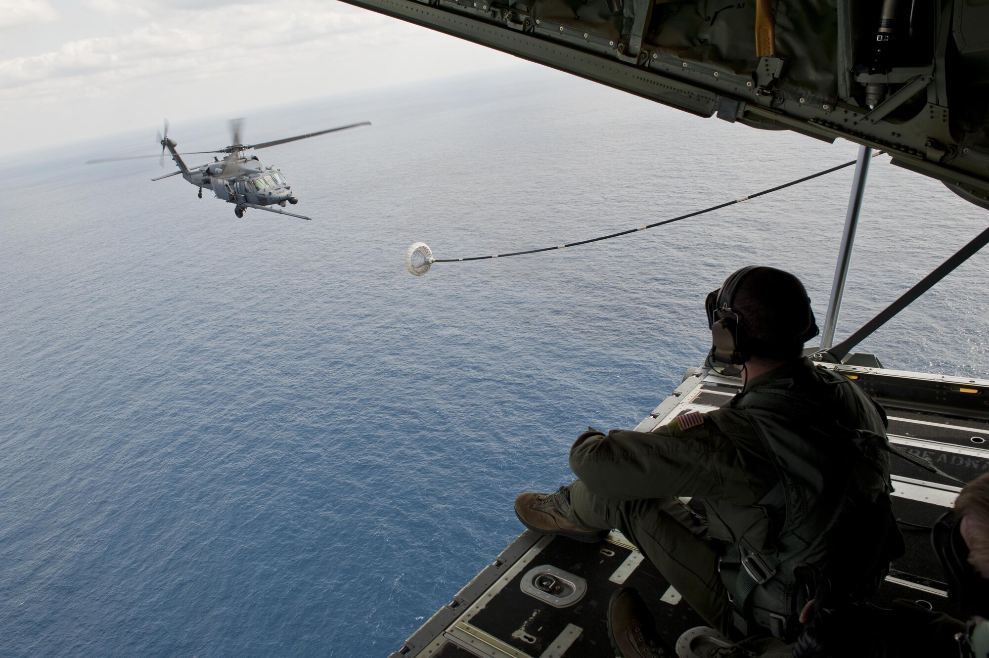 U.S. Air Force Senior Airman Zach Harmon, 17th Special Operations Squadron MC-130J Commando II loadmaster, observes a 33rd Rescue Squadron HH-60G Pave Hawk helicopter air-to-air refueling during a training exercise Feb. 17, 2016, off the coast of Okinawa, Japan. The 17th SOS simulated a quick-reaction, full-force sortie that tested the unit's mobilization of the entire MC-130J fleet. (U.S. Air Force photo by Senior Airman Peter Reft/Released)