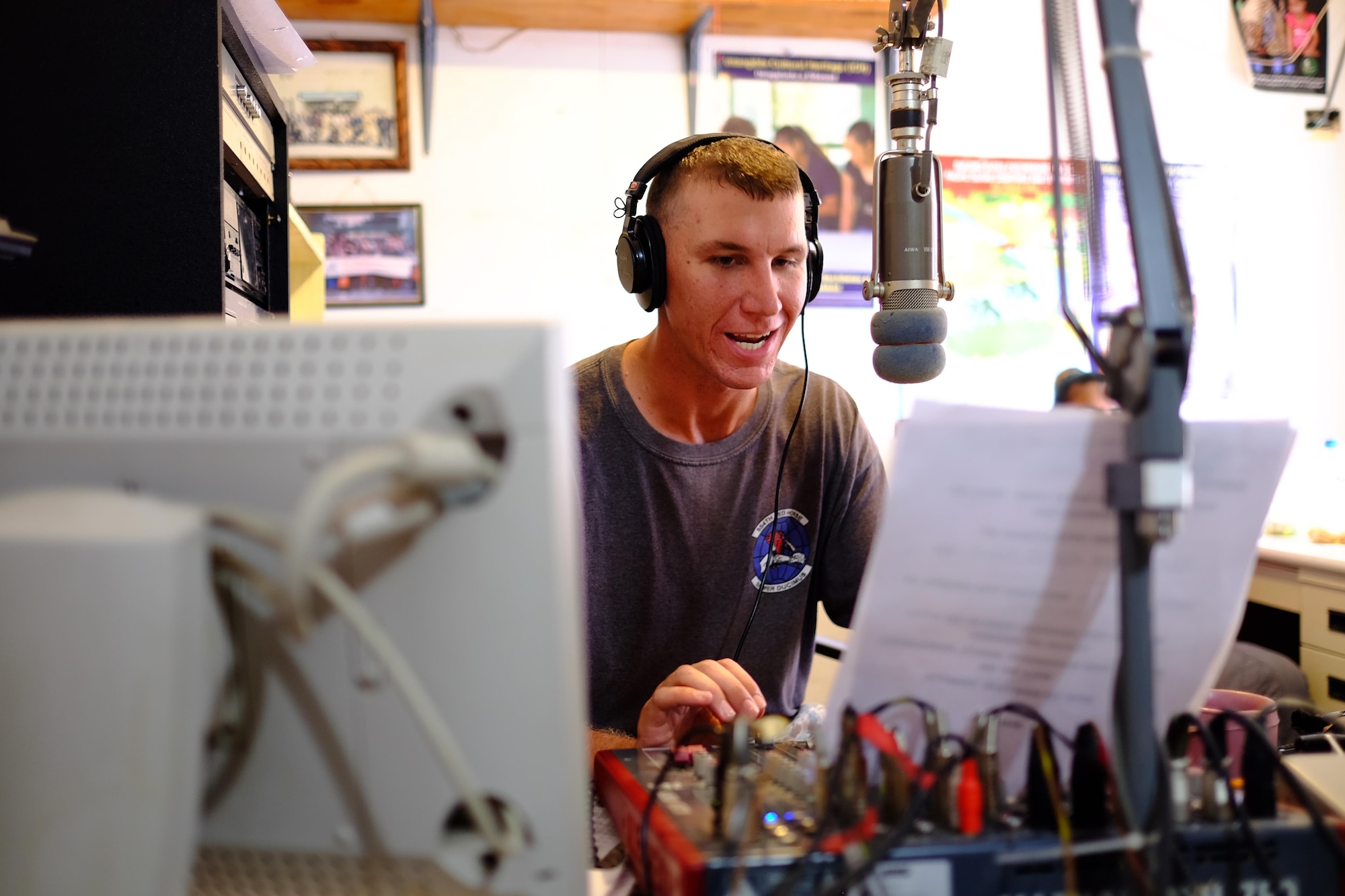U.S. Air Force Senior Airman Lucian Root, Civil Action Team 554-01 structural journeyman from the 36th Civil Engineer Squadron at Andersen Air Force Base, Guam, speaks into the microphone during a radio show, Feb. 18, 2016. Root, along with other members of CAT 554-01, hosted a radio program every week informing listeners about current and completed projects, along with playing American music. (U.S. Air Force photo by Staff Sgt. Christopher Stoltz/Released)
