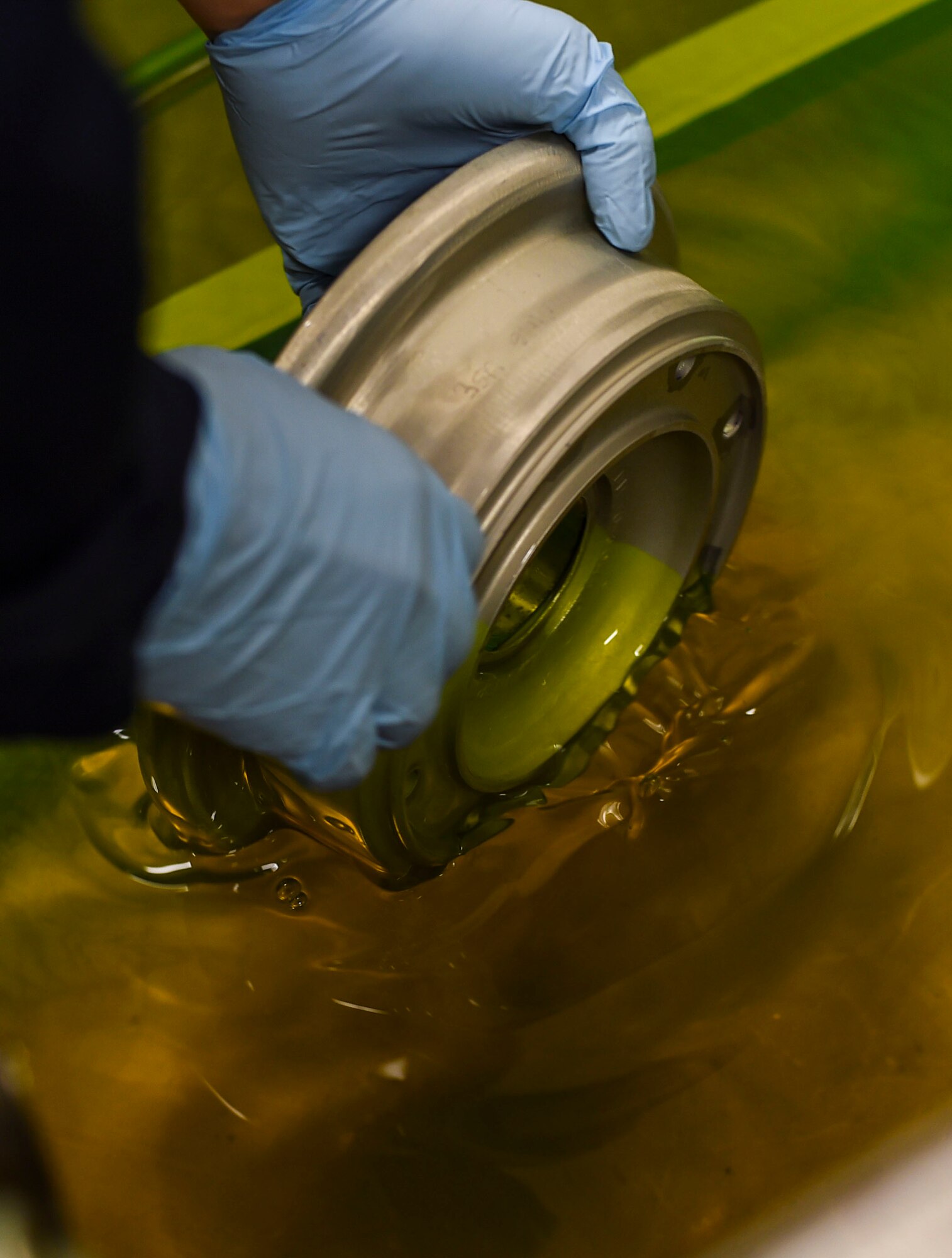 Airman 1st Class David Frias, a 49th Maintenance Squadron non-destructive inspection technician, dips a metal part in a chemical penetrant at Holloman Air Force Base, N.M. on Feb. 22. The item is dipped in a low-viscosity penetrant, which fills any voids left by cracks or damage, and indicates a need for repair. NDI technicians are able to assist aircraft maintainers by identifying aircraft damage, allowing them to ensure military aviation equipment safety. (U.S. Air Force photo by Senior Airman Leah Ferrante)