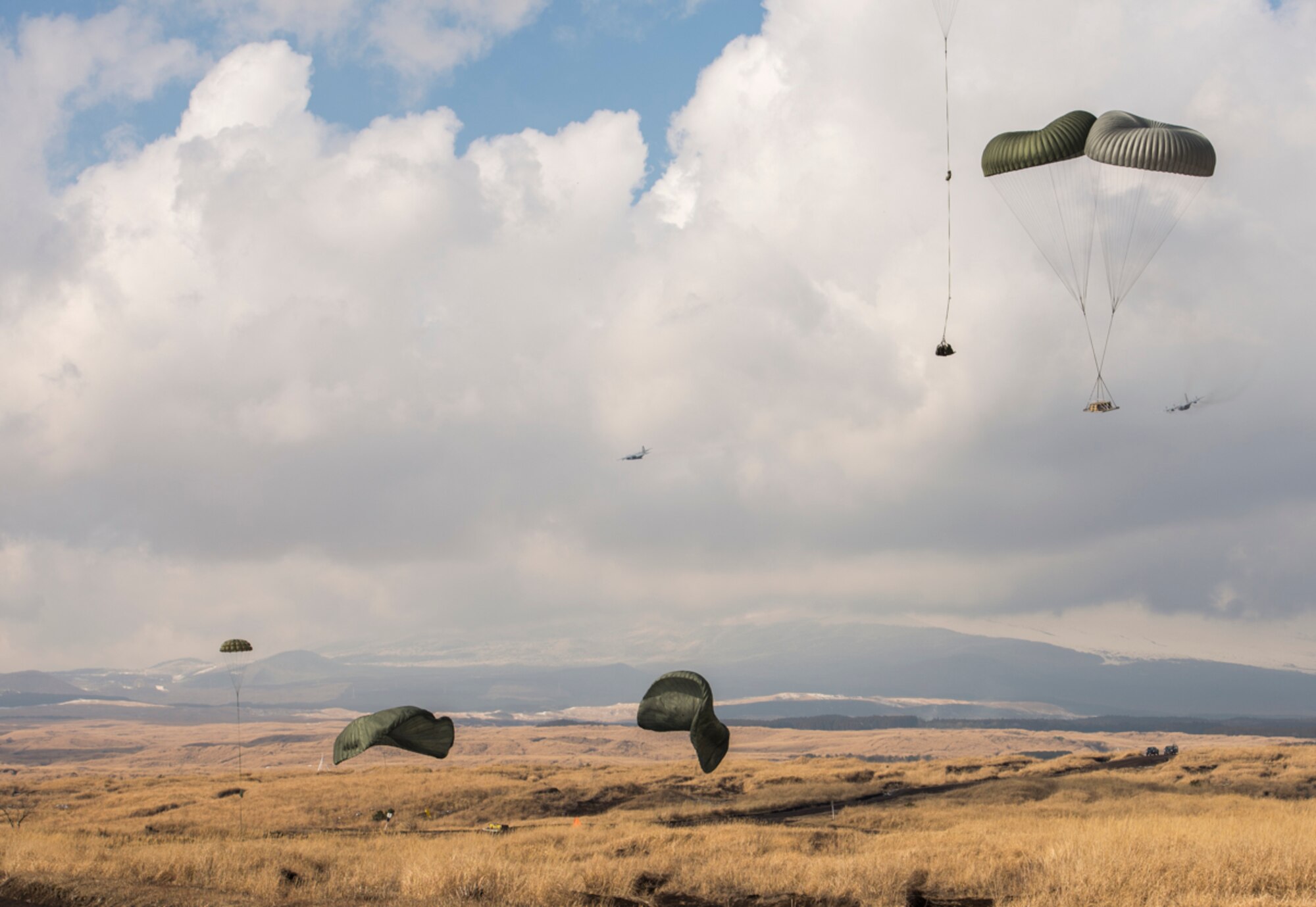 Two C-130 Hercules complete pallet drops at the base of Mt. Fuji, Japan, Feb. 2, 2016. The 374th Logistics Readiness Squadron spent hours constructing each pallet and packing the parachutes. After the drop they searched and recovered them for reuse. (U.S. Air Force photo by Airman 1st Class Elizabeth Baker/Released)