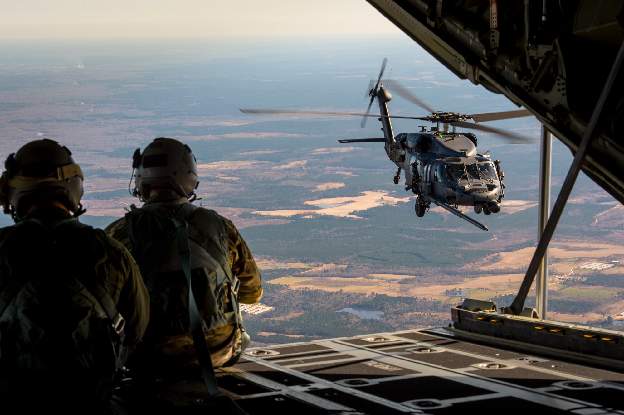 U.S. Air Force Senior Airman Kevin O’Neil, left, and Tech. Sgt. Christopher Reynolds, 71st Rescue Squadron loadmasters, signal to an HH-60G Pave Hawk from the back of an HC-130J Combat King II during aerial refueling operations, Feb. 18, 2016, in the skies over Moody Air Force Base, Ga.  Multiple U.S. Air Force aircraft within Air Combat Command conducted joint aerial training at Grand Bay Bombing and Gunnery Range. During the training, the aircraft conducted tactical air and ground maneuvers, as well as weapons training. (U.S. Air Force photo by Senior Airman Ryan Callaghan/Released)


