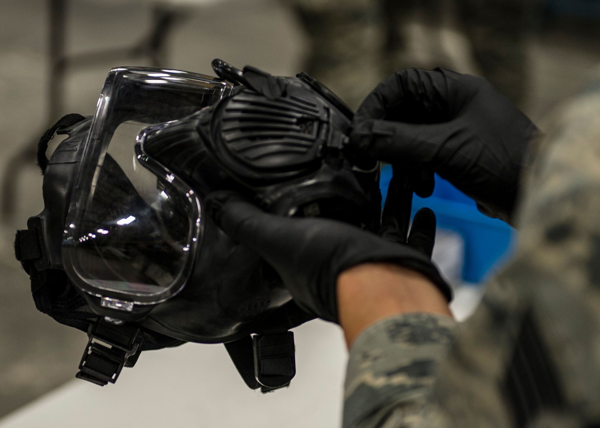 Senior Airman Darius Heggs, 92nd Logistics Readiness Squadron individual protection equipment journeyman, explains how to dismantle a M50 gas mask to Tech Sgt. Rosalinda Sanchez, 92nd LRS NCO in charge of receiving, during a gas mask and weapons class Feb. 18 2016, at Fairchild Air Force Base, Wash. Participants in the class range from new Airmen to NCOs and even commanders. (U.S. Air Force photo/Airman 1st Class Sean Campbell)