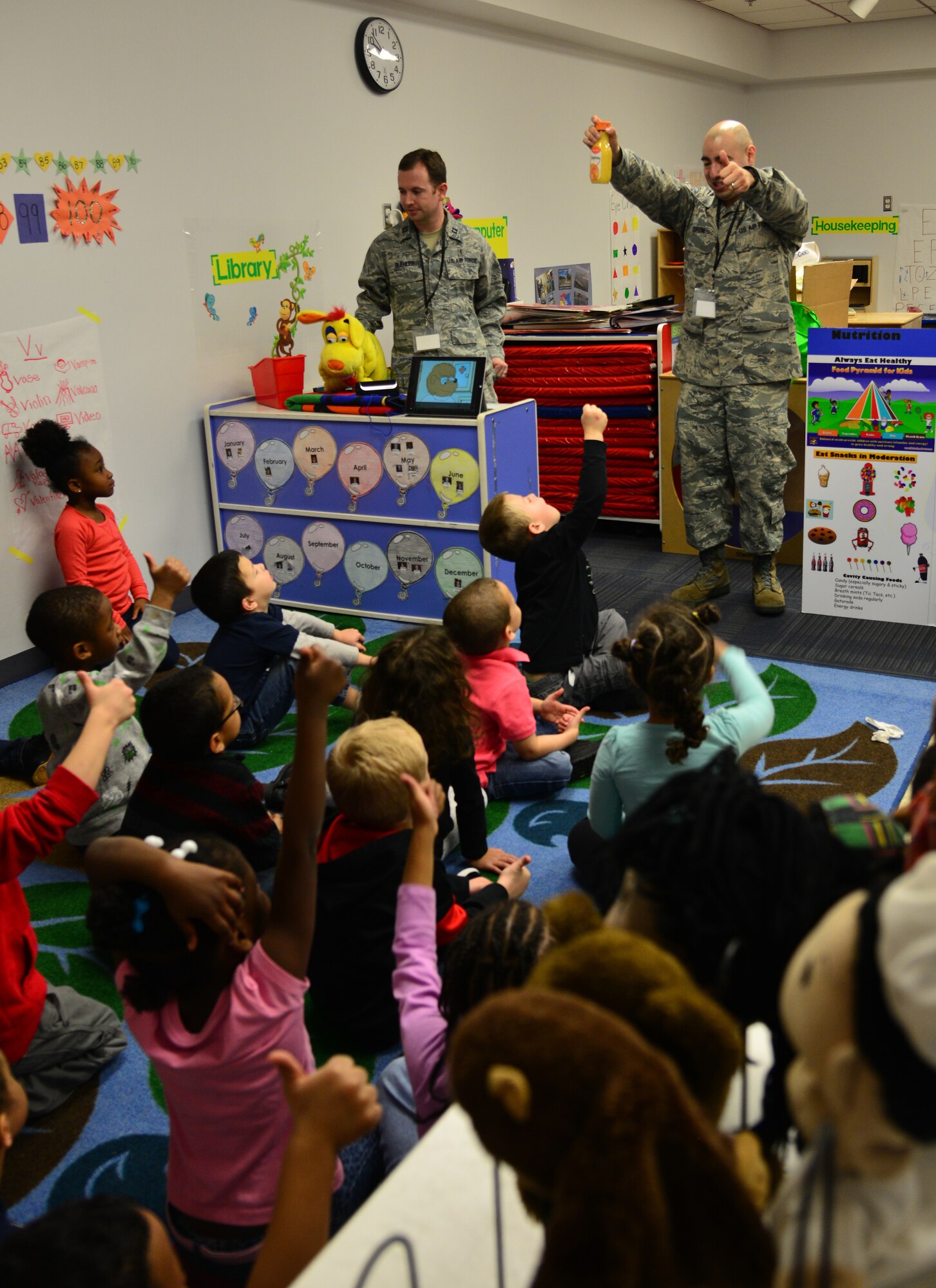 U.S. Air Force Dr. (Capt.) Trent Buehler, dentist assigned to the 633rd Dental Squadron, and Tech. Sgt. Keith Duron, dental hygienist at the 633rd DS, ask children to identify healthy food and beverages at Langley Air Force Base, Va., Feb. 23, 2016. The children signaled with a thumbs-up or thumbs-down in determining whether beverages like orange juice and soda were good or bad for their teeth. (U.S. Air Force photo by Staff Sgt. Aubrey White)