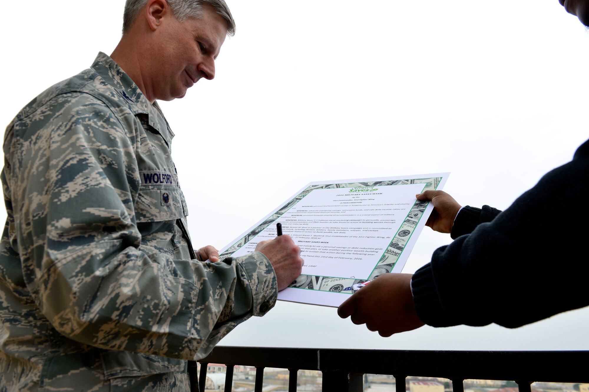 Colonel Bryan Wolford, 31st Fighter Wing vice commander, signs the official Military Saves Week proclamation, Feb. 23, 2016, at Aviano Air Base, Italy. Military Saves Week encourages Team Aviano members to reduce personal debt and build wealth. (U.S. Air Force photo by Airman 1st Class Cary Smith/Released)