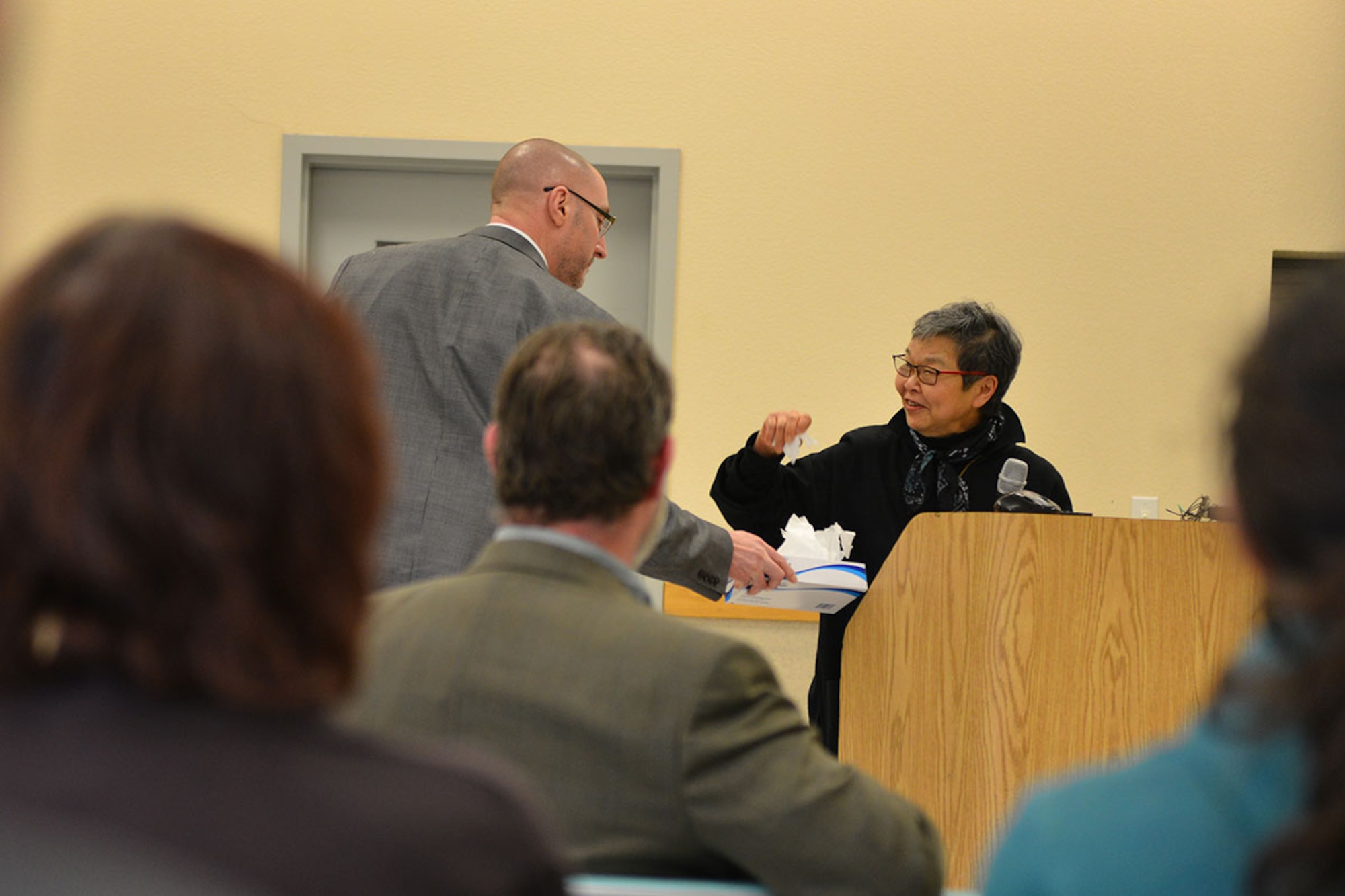 Mary Abo, daughter of John Tanaka, who was arrested and interned out of Juneau, Alaska, accepts tissues as she shares her childhood memories at Joint Base Elmendorf-Richardson's Day of Remembrance ceremony, Feb. 19 at the Army Reserve Center. The ceremony highlighted findings on JBER-Richardson's internment camp and was held in honor of the men, women, and children of Japanese descent who were interned by the U.S. during World War II. (U.S. Air Force photo by Airman 1st Class Kyle Johnson)