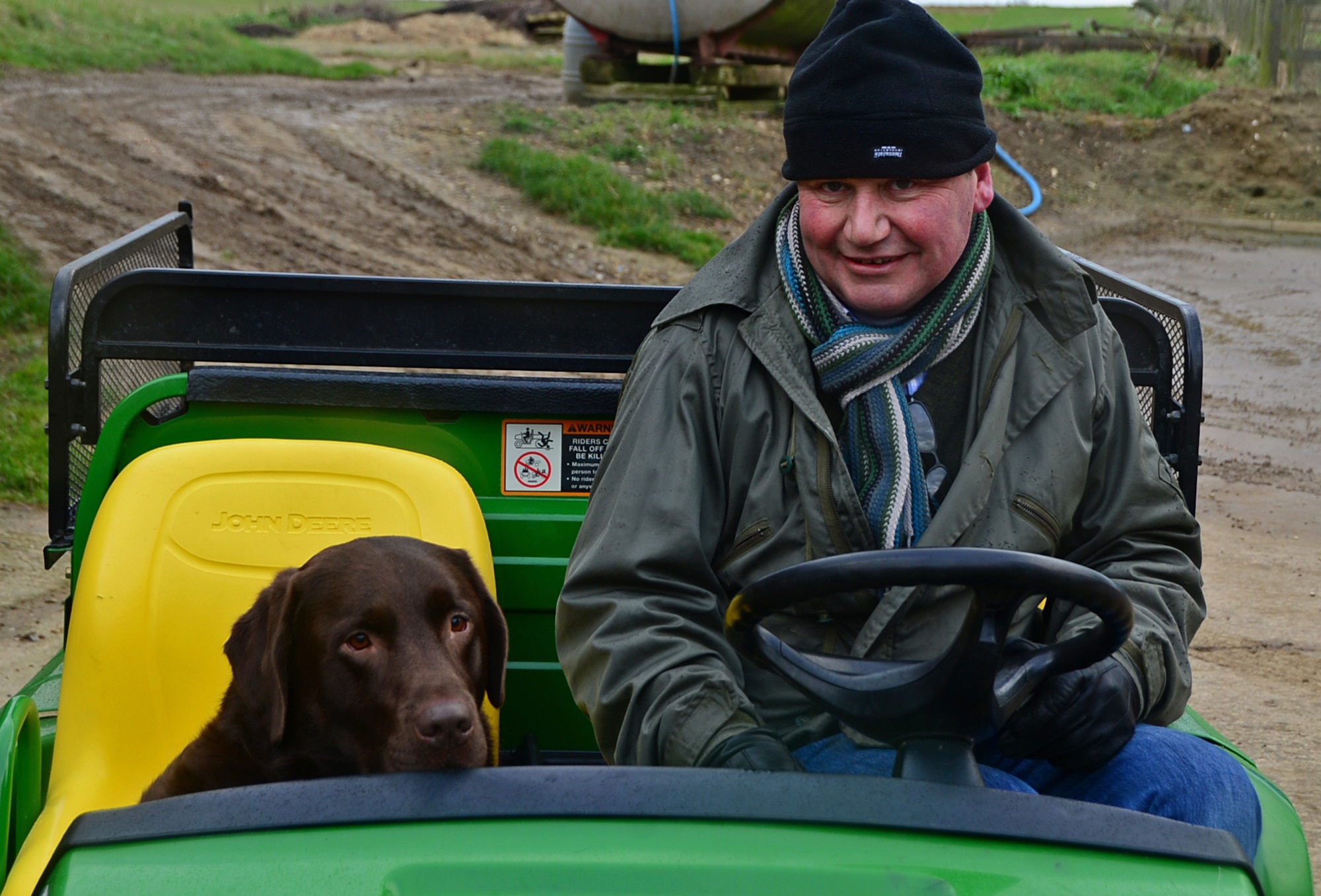 Andrew Aves, farm-owner near Hinderclay, England, and his dog, Roland, ride in a gator on his property, Feb. 4, 2016.  Aves supports and hosts military training exercises on his land by allowing various bases across Europe, including personnel assigned to Royal Air Force bases, to train and operate on his property. (U.S. Air Force photo/Senior Airman Erin Trower) 