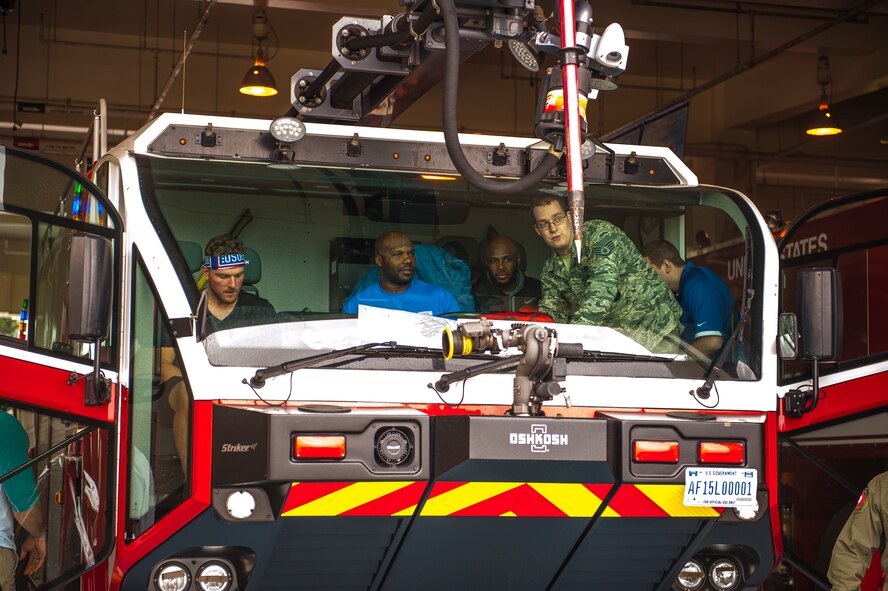 Members of the Indianapolis Colts and the 18th Civil Engineer Squadron during a demonstration of fire truck capabilities by Staff Sgt. Craigery Hassinger, a fire fighter with the 18th CES, Feb. 19, 2016, at the 18th CES at Kadena Air Base, Japan. The Colts received demonstrations of different equipment used throughout the base. (U.S. Air Force photo by Airman 1st Class Nick Emerick) 
