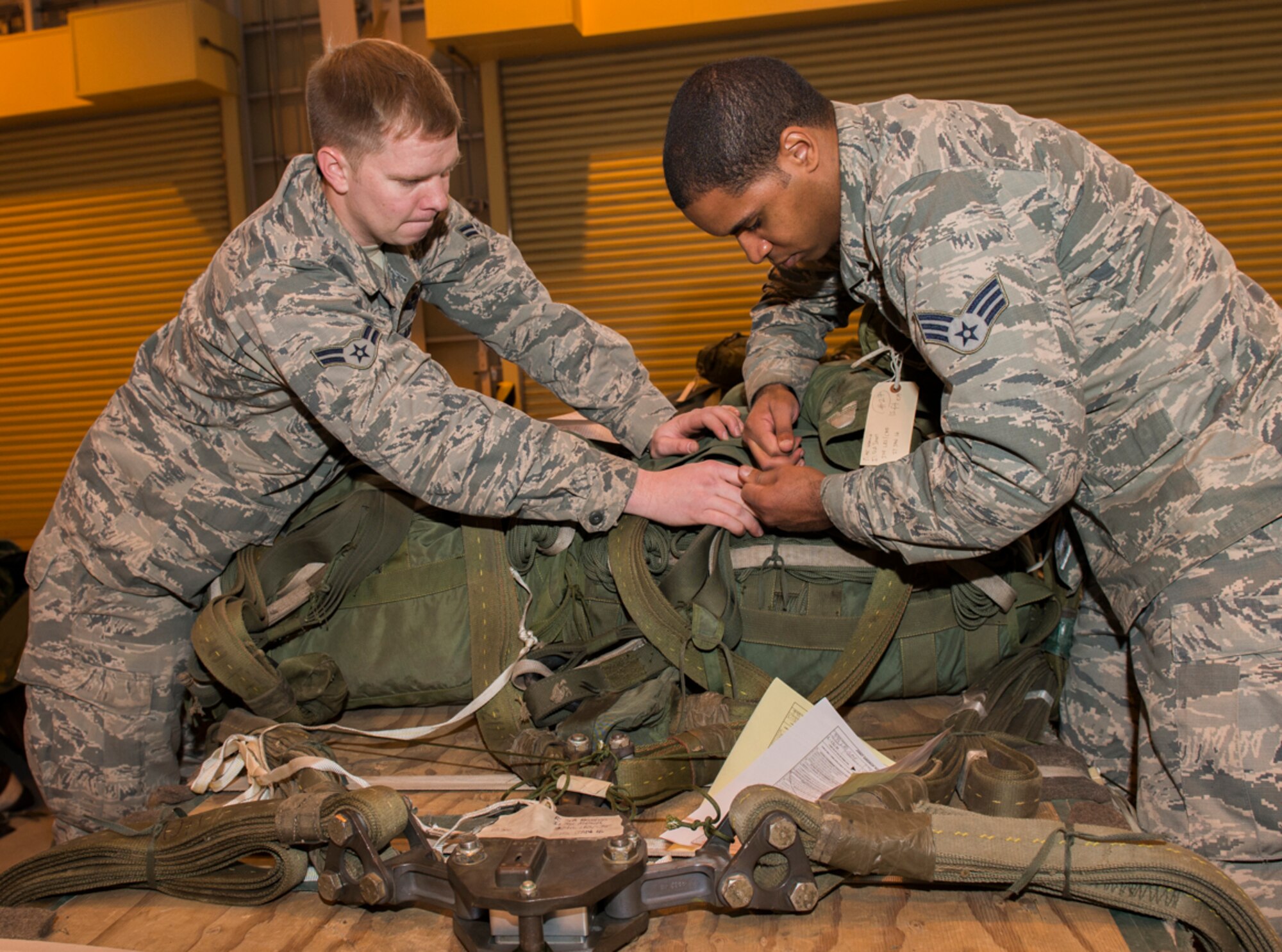 Airman 1st Class John Marcum and Senior Airman Brandon Roden, 374th Logistics Readiness Squadron air transportation specialists, secure parachutes to a pallet at Yokota Air Base, Japan, Feb. 1, 2016. The Pacific Air Forces heavily rely on the 374 LRS as one of the few units qualified to conduct critical final inspections on cargo and to inspect cargo that requires special attention. They can be called on at a moment’s notice to support any location in PACAF. (U.S. Air Force photo by Airman 1st Class Elizabeth Baker/Released)