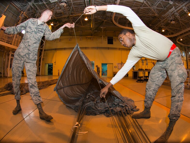 Airman 1st Class Shawn Stickle and Airman 1st Class Armond Smith, 374th Logistics Readiness Squadron air transportation specialists, inspect a parachute for repairs at Yokota Air Base, Japan, Feb. 1, 2016. The 374 LRS prepares parachutes and pallets to support the 36th Airlift Squadron in airdrop exercises. (U.S. Air Force photo by Airman 1st Class Elizabeth Baker/Released)