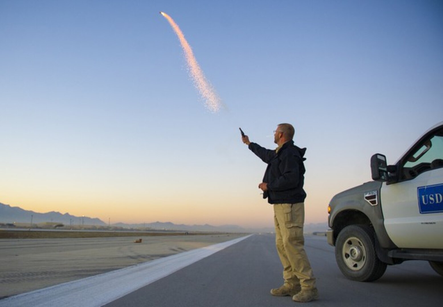 Wildlife biologist Scott Stopak, from the United States Department of Agriculture-Wildlife Services, fires off a pyrotechnic screamer on the flight line at Bagram Air Field, Afghanistan, Feb. 24, 2016. (U.S. Air Force photo by Capt. Bryan Bouchard)