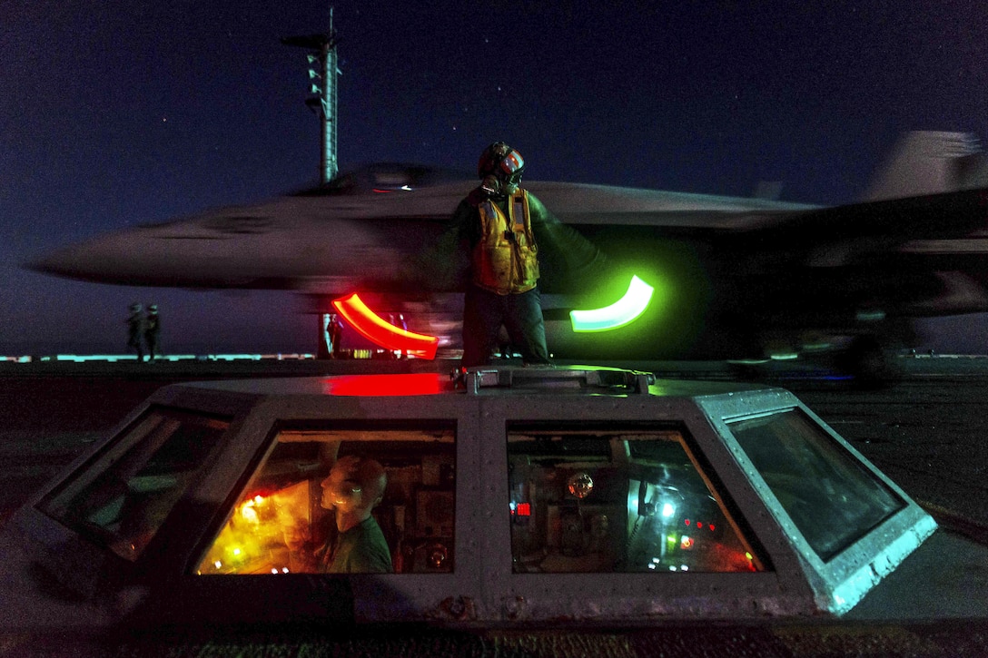 Navy Petty Officer 2nd Class Matthew Fulks motions to crew members on the flight deck of the aircraft carrier USS John C. Stennis in the Philippine Sea, Feb. 24, 2016. The Stennis provides a ready force to support security and stability in the Indo-Asia-Pacific region. U.S. Navy photo by Seaman Cole C. Pielop