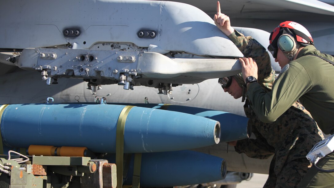 Cpl. Ross McClanahan signals to a Marine operating an A/S 32K-1A/1B/1C SATS Weapon Loader to load BDU-45 practice bombs onto an F/A-18 Hornet during Exercise Coastal Predator at Marine Corps Air Station Cherry Point, N.C., Feb. 16, 2016. The practice bombs are unguided ordnance that fall according to the trajectory of the aircraft while in flight and are used for training purposes. Coastal Predator is an exercise that included Marine Corps and Army aviation assets along with Air Force personnel and civilian contractors to conduct Forward Air Controller Airborne training in accordance with the pre-deployment training program. 