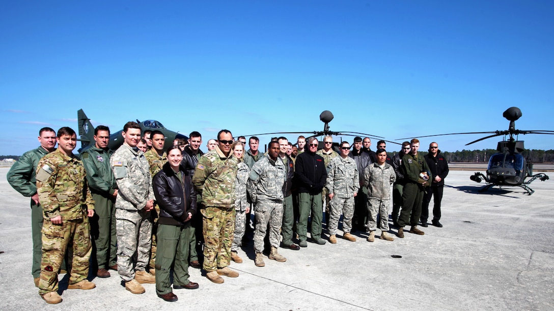Active duty and retired service members pose for a photo in front of two OH-58 Kiowas and an A-4 Skyhawk during Exercise Coastal Predator at Marine Corps Air Station Cherry Point, N.C., Feb. 19, 2016. Coastal Predator is an exercise that included Marine Corps and Army aviation assets along with Air Force personnel and civilian contractors to conduct Forward Air Controller Airborne training in accordance with the pre-deployment training program. 