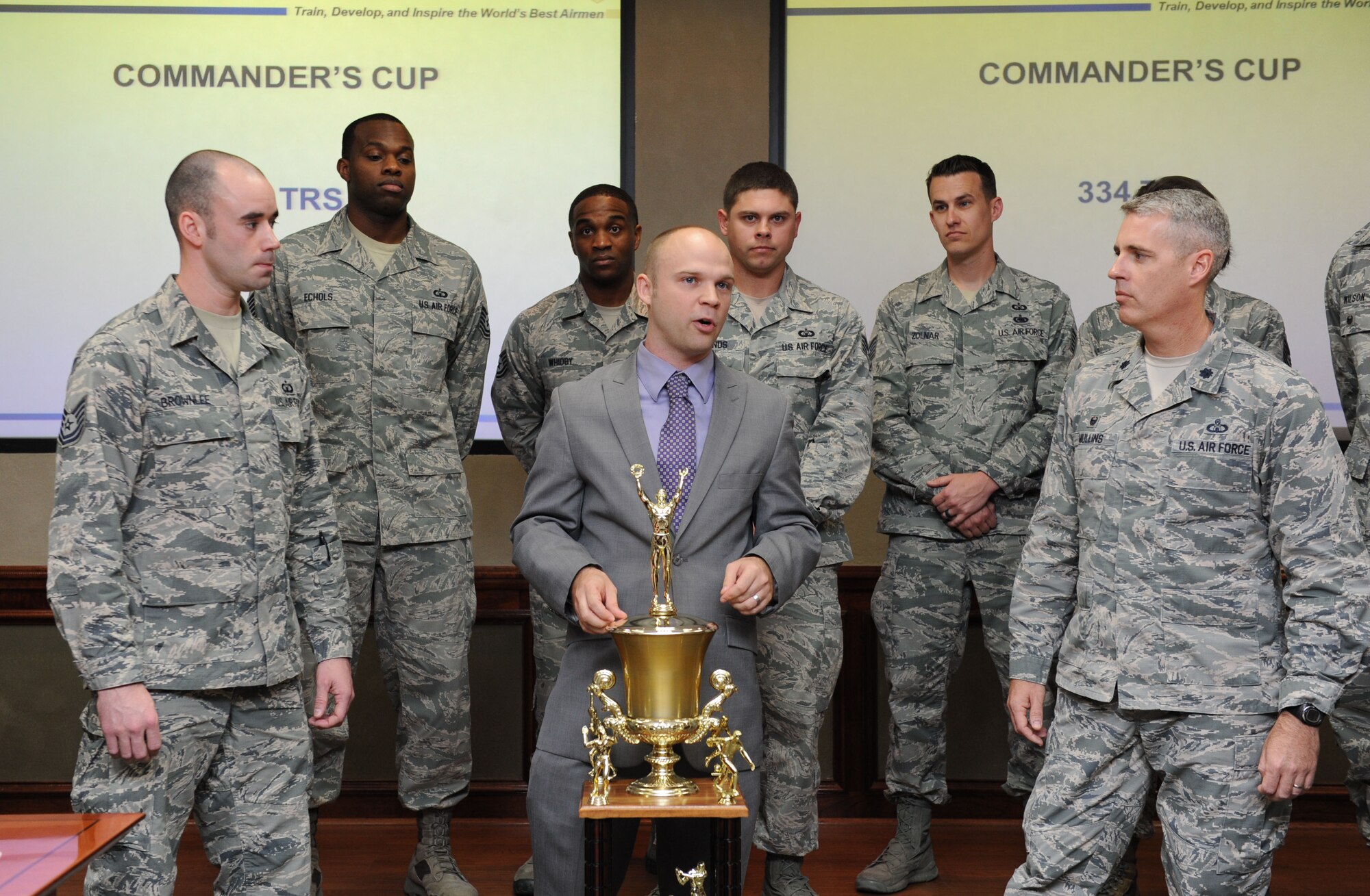 Jake Regal, Keesler sports director, presents the commander’s trophy to the 334th Training Squadron at Stennis Hall Feb. 24, 2016, Keesler Air Force Base, Miss. The competition is centered around points awarded to a squadron based on their participation in the intramural sports program and special events facilitated by the base fitness centers. This is the 6th consecutive year the “Gators” have earned the trophy. (U.S. Air Force photo by Kemberly Groue)