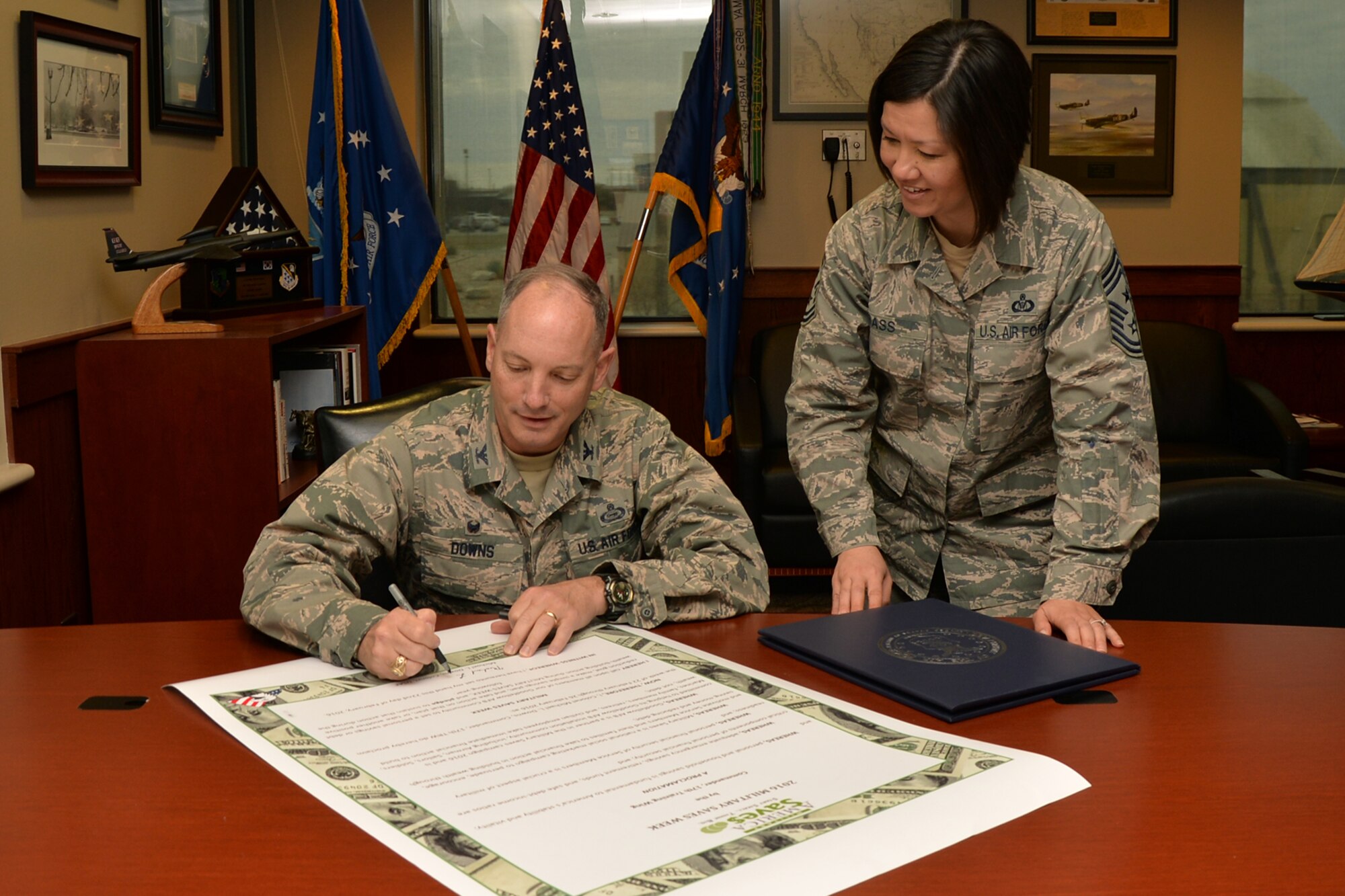 U.S. Air Force Col. Michael L. Downs, 17th Training Wing Commander, signs a proclamation with Chief Master Sgt. JoAnne S. Bass, 17th TRW Command Chief, to start off the Military Saves Campaign on Goodfellow Air Force Base, Texas, Feb. 22, 2016. The MSC is a Defense Department Initiative as part of a year-long effort in conjunction with a larger nationwide America Saves campaign. (U.S. Air Force photo by Airman 1st Class Randall A. S. Moose/Released)