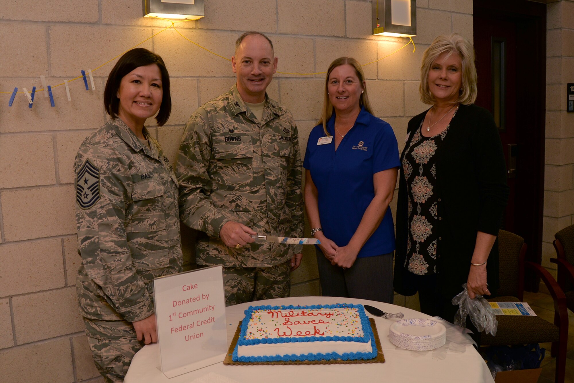 U.S. Air Force Chief Master Sgt. JoAnne S. Bass, 17th Training Wing Command Chief; Col. Michael L. Downs, 17th TRW Commander, Amanda Gannon, 1st Community Federal Credit Union business development, Cheryl Book, 1st CFCU business development, prepare to cut a cake served for the Military Saves Campaign on Goodfellow Air Force Base, Texas, Feb. 22, 2016. The Airman and Family Readiness Center plans to host a variety of classes with an emphasis on saving money, retirement plans and improving credit scores. (U.S. Air Force photo by Airman 1st Class Randall A. S. Moose/Released)