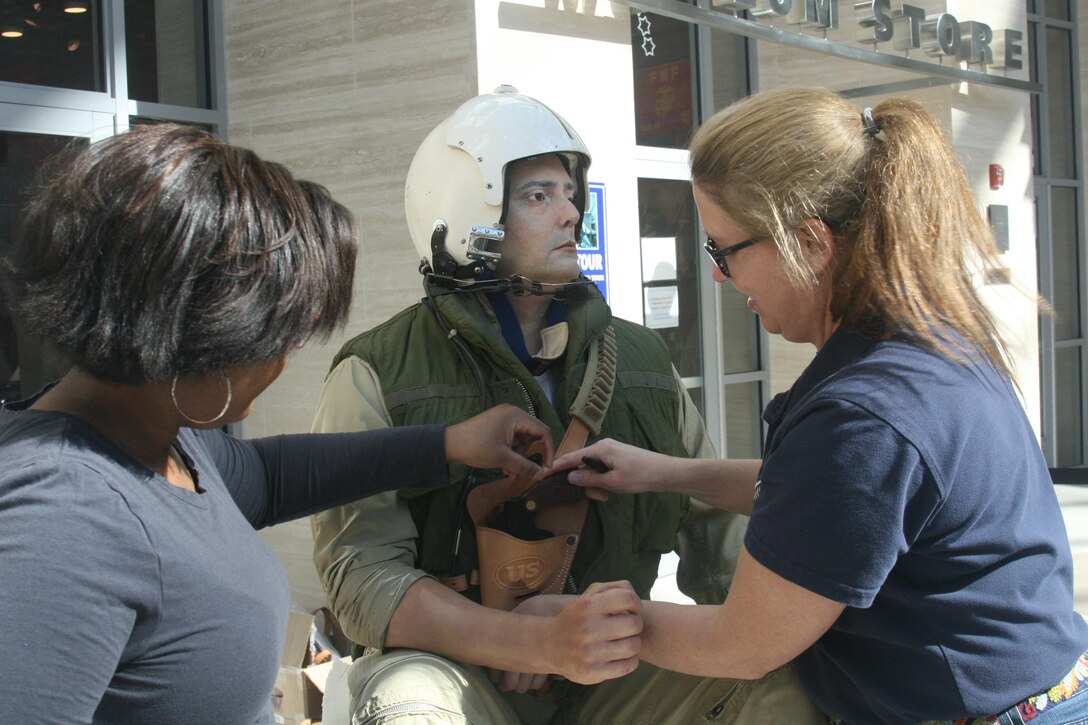 Intern Brianna Nunez-Franklin and Exhibit Specialist Alice Webb adjust the holster on the figure of Gunnery Sgt. James Breedlove. Breedlove’s figure will be the copilot of a UH-34D helicopter in a new exhibit at the National Museum of the Marine Corps.