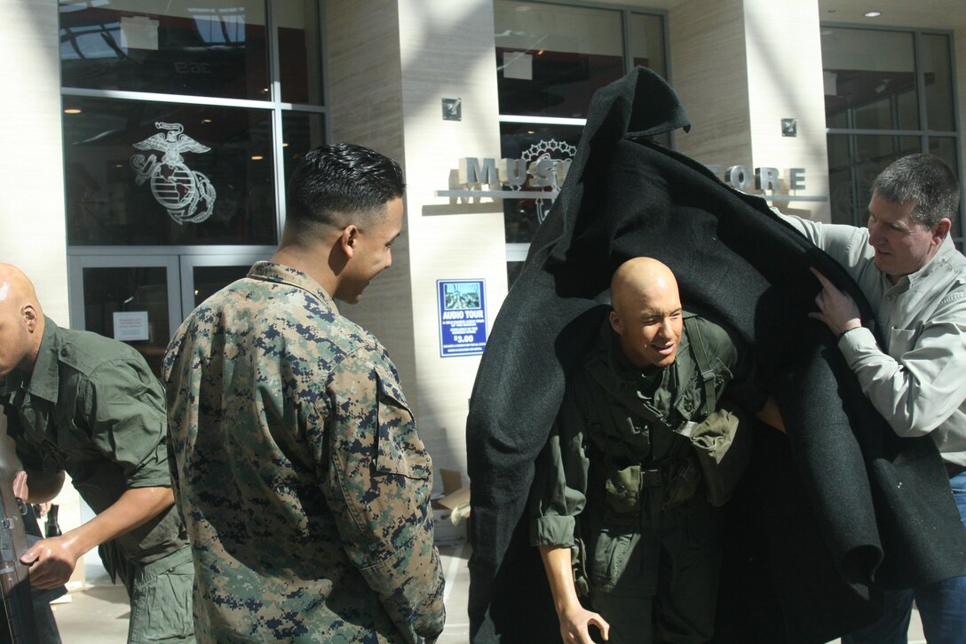 Cpl. Jhon Espinal watches as Chuck Girbovan, exhibit services chief, unveils the cast figure Espinal modelled for last year. Espinal's figure, an ammunition carrier, will be shown deploying from a UH-34D helicopter into a rice paddy in a scene set in 1965, during the Vietnam War. The scene will be visible at the National Museum of the Marine Corps when the museum reopens after a three-month closure April 1. Espinal met his cast figure Feb. 18.