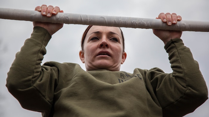 Major Misty Posey demonstrates proper form for pull-ups to Marines at Marine Corps Base Quantico, Virginia, Feb. 19, 2016. Posey, a plans officer for Manpower Integration, developed a pull-up program to assist Marines with their pull-ups and proper form. 