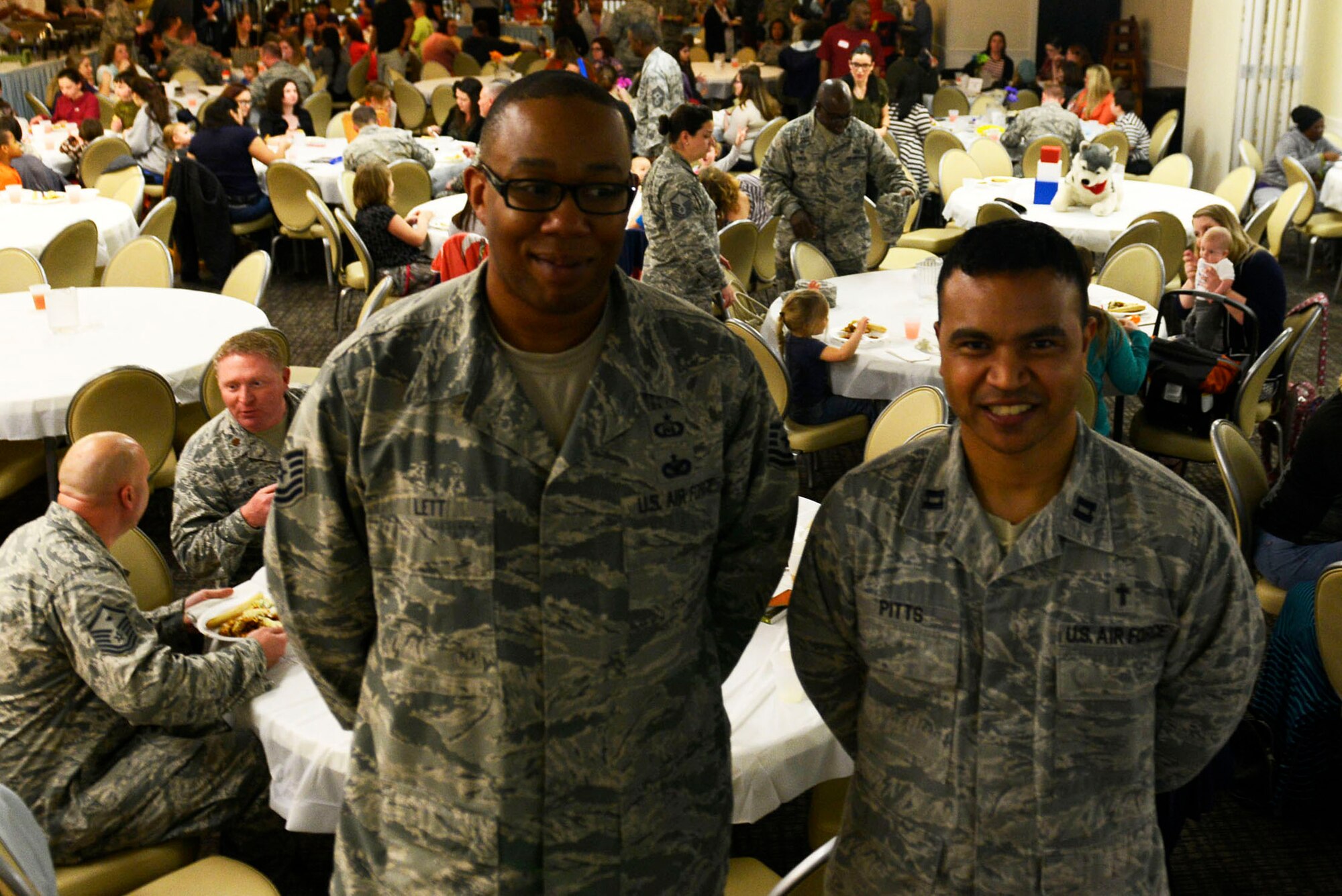 U.S. Air Force Tech. Sgt. Jamyal Lett, 20th Fighter Wing NCO in charge of chapel readiness (left), and Chaplain (Capt.) Robert Pitts, 20th Fighter Wing chaplain (right), stand in front of the deployed family dinner at Shaw Air Force Base, S.C., Feb. 22, 2016. Hosted by the 20th Fighter Wing Chaplain Corps, the dinner gave families of deployed service members the opportunity to share in a meal and network with others in similar situations, while building fellowship and getting to know their Airman’s leadership. (U.S. Air Force photo by Airman 1st Class Christopher Maldonado)