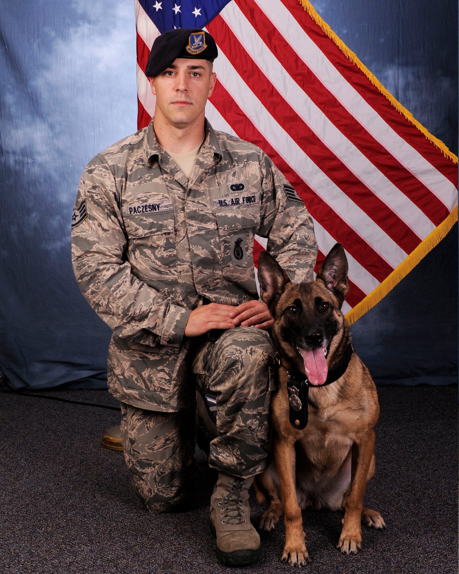 Staff Sgt. Justin Paczensy, 325th Security Forces military working dog handler, poses for a photo with MWD Mica Jan. 11, at the public affairs studio. Military working dog Mica retired from active duty Feb. 19, after a post-deployment medical check revealed she had an aggressive form of cancer. Mica was later adopted by Maj. Mari Metzler, 325th Aerospace Medical Squadron aerospace physiology flight commander. (Courtesy photo)

