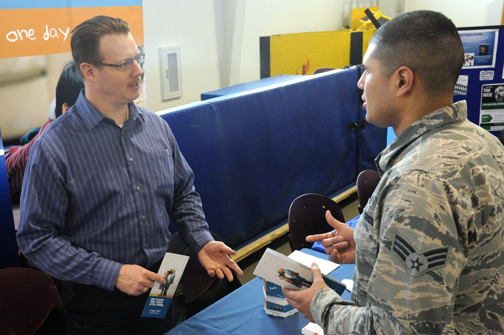 Senior Airman Maximiliano Estrada, assistant to the 319th Air Base Wing Command Chief, speaks to Lance Hill, College SAVE representative, during the Military Saves Financial Fair on Grand Forks Air Force Base, N.D., Feb. 25, 2015. Hill was one of several agency representatives sharing financial advice and information at the fair, which was hosted by the Airman & Family Readiness Center. (U.S. Air Force photo by Tech. Sgt. David Dobrydney/released)