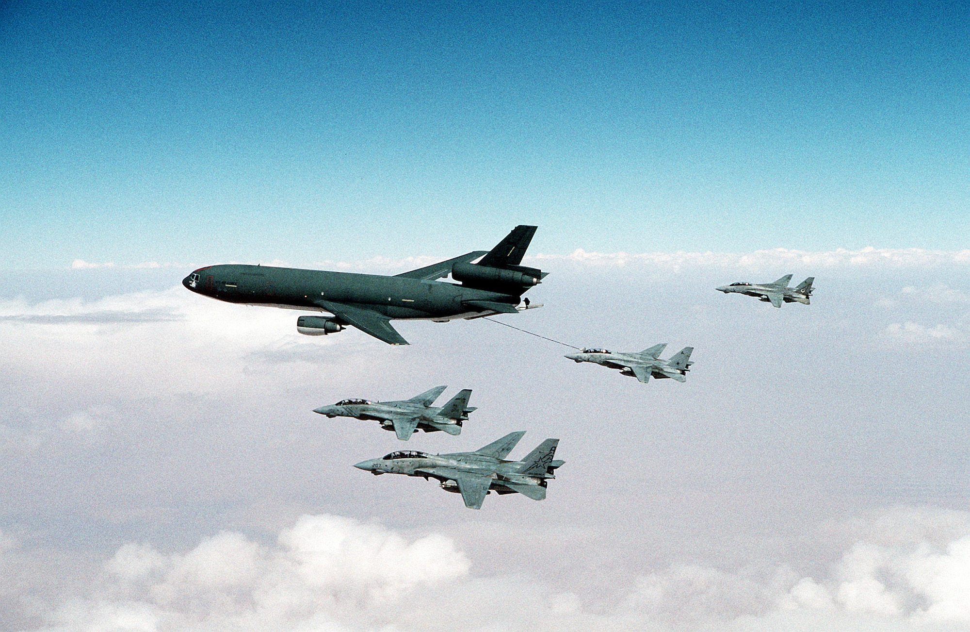An F-14A Tomcat refuels from a U.S. Air Force KC-10A Extender as other Tomcats fly in formation, during Operation Desert Storm. Squadrons represented by the aircraft are (from foreground) Fighter Squadron 33 (VF-33), Fighter Squadron 84 (VF-84) and Fighter Squadron 14 (VF-14). (Courtesy photo)