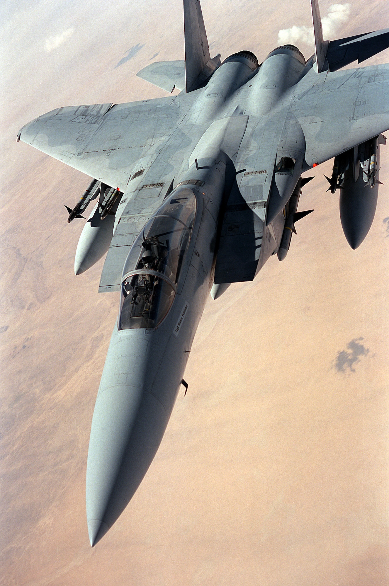 An F-15 Eagle flies a patrol over the desert during the cease-fire between coalition and Iraqi forces following Operation Desert Storm. The aircraft is carrying four AIM-9 Sidewinder missiles on its wing pylons and an AIM-7 Sparrow missile beneath its fuselage. (Courtesy photo)