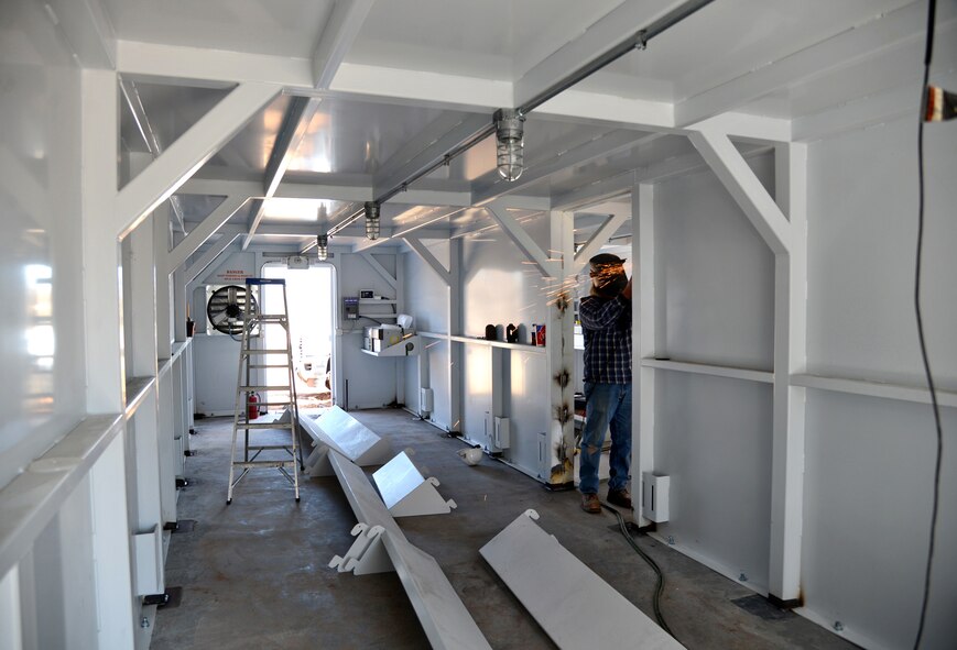Michael Layton, a worker with Survive-A-Storm Shelters, grinds down welding marks in the new storm shelter currently being installed directly north of the Tinker Youth Center. Four 10x40 units, which have been welded together and reinforced into the ground, are rated to survive F5 winds. The shelter will hold approximately 390 people and will be ready for emergency use for Oklahoma’s unpredictable spring weather.  (Air Force photo by Kelly White/Released)