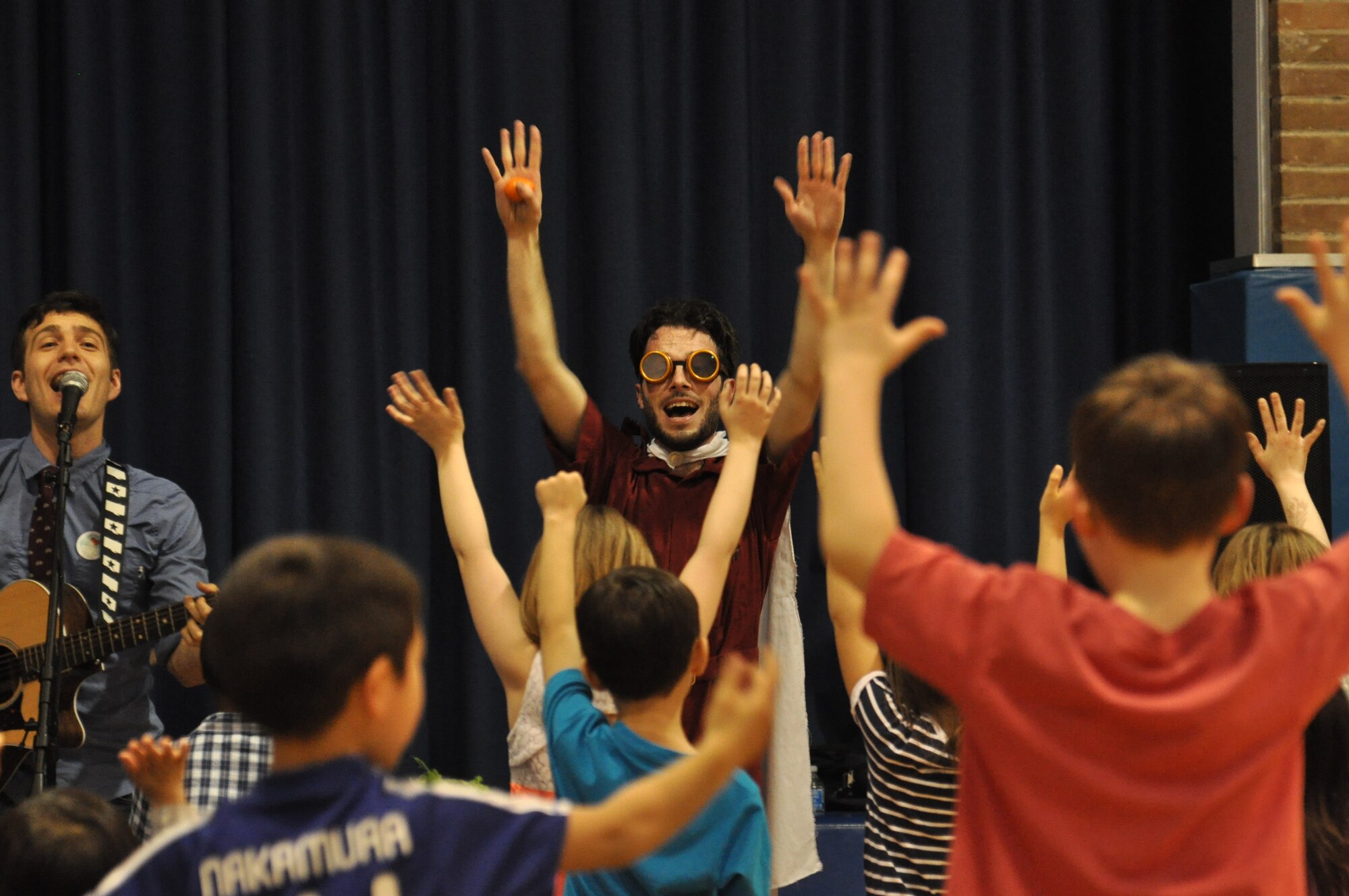 Children reach for the sky as band member, Alex “Jumpsuit” MacDonald of the Tim and the Space Cadets, demonstrates to them that their “sky” is unlimited at the Prairies Youth Center at Wright-Patterson AFB. (U.S. Air Force photo/Myra Saxon)