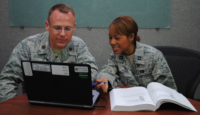 Maj. Mike Low and Capt. Cherelle Small, instructors at the Air Force Institute of Technology School of Systems and Logistics, collaborate on course material at Wright-Patterson Air Force Base. (U.S. Air Force photo/Dennis Stewart)